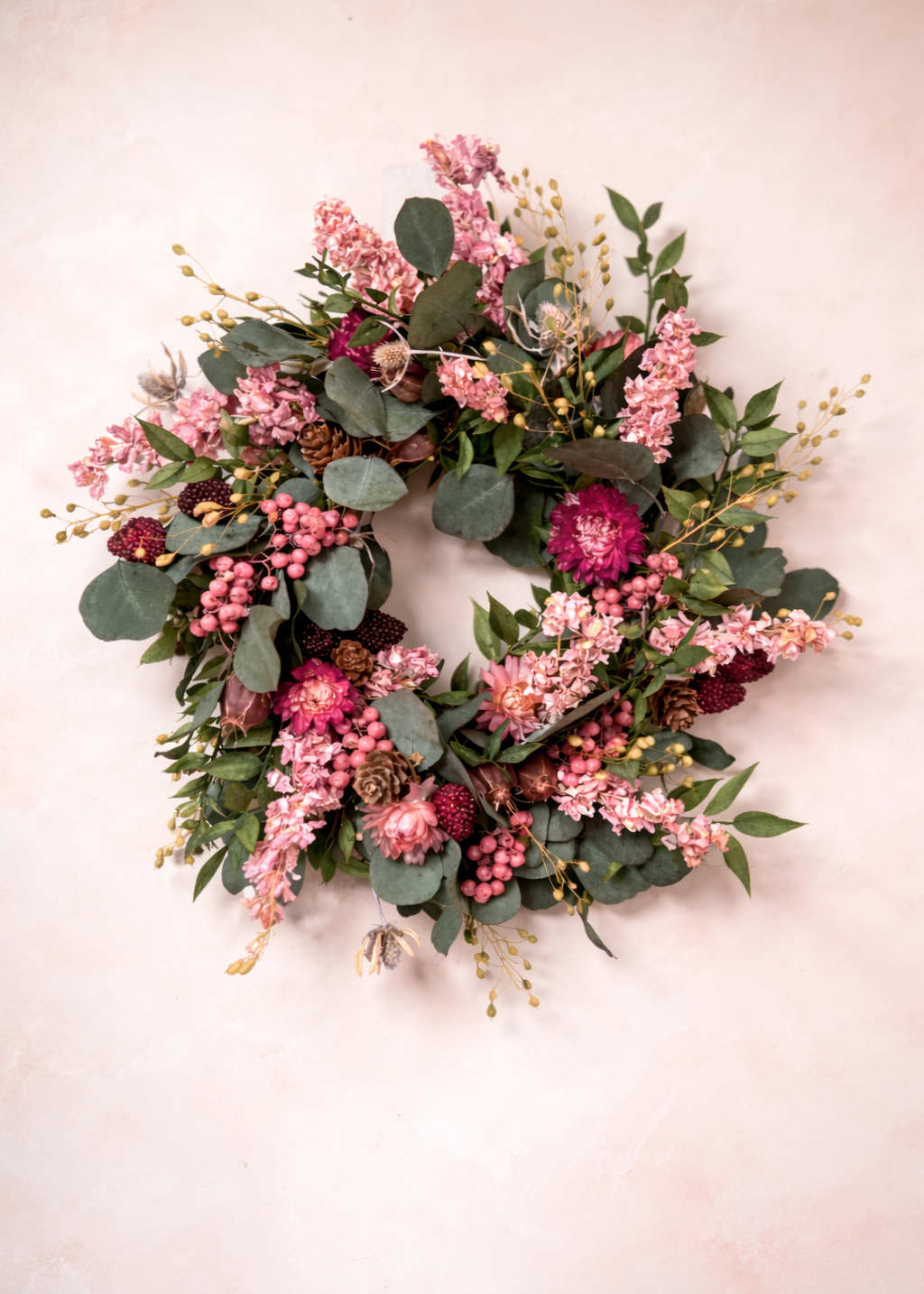 Floral wreath with pink and green flowers on a light background