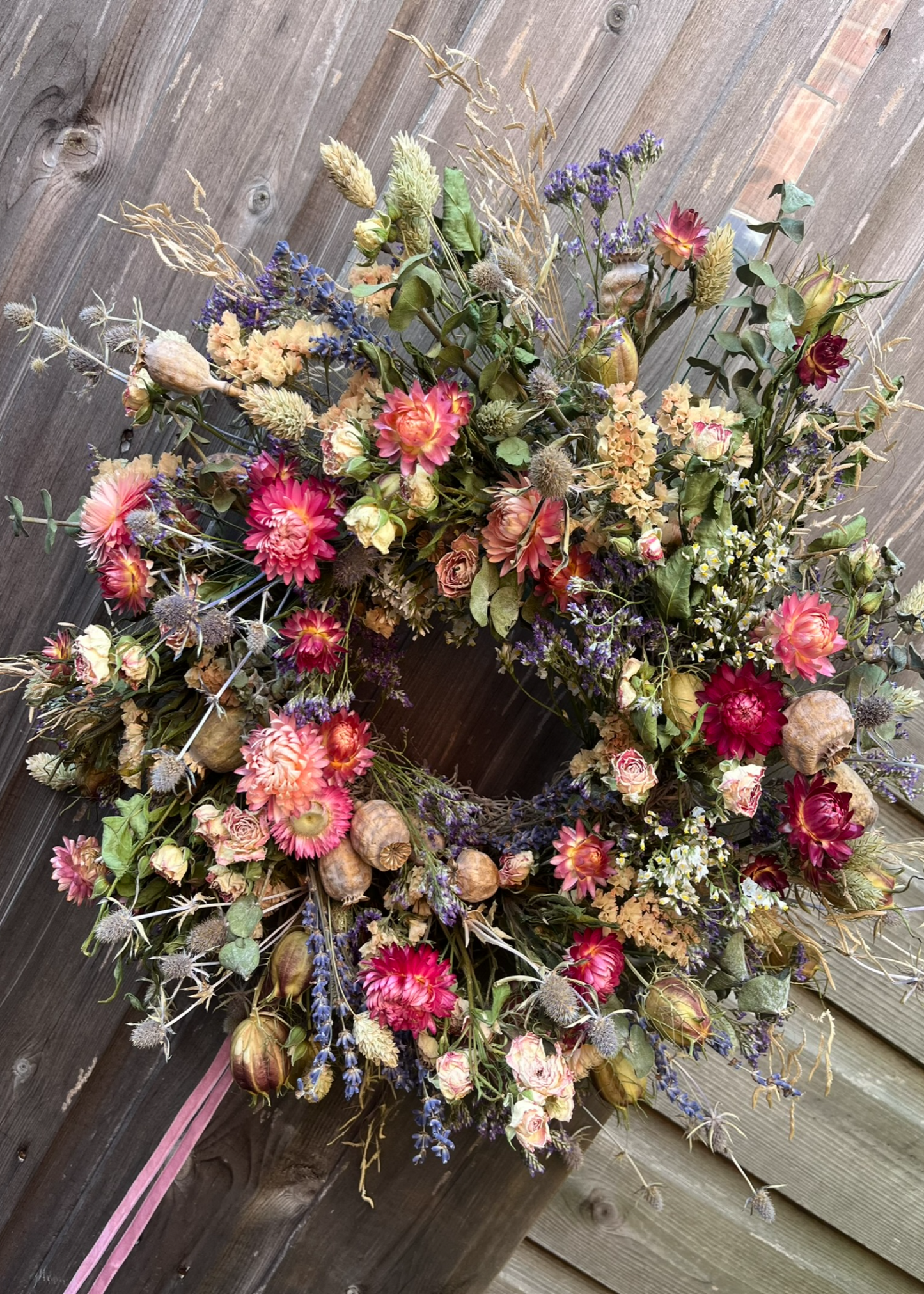 Floral wreath with pink and green flowers on a wooden door