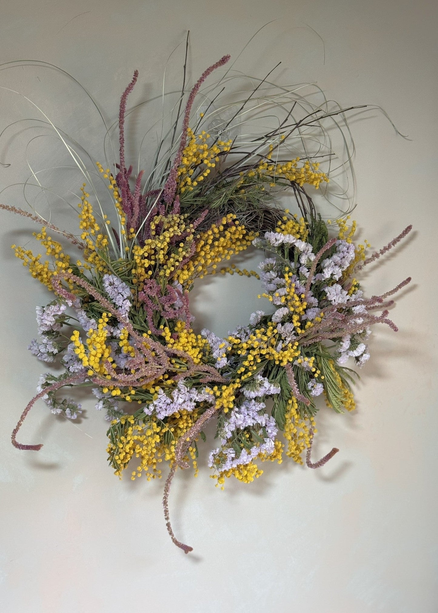Decorative wreath with yellow and purple flowers on a plain background