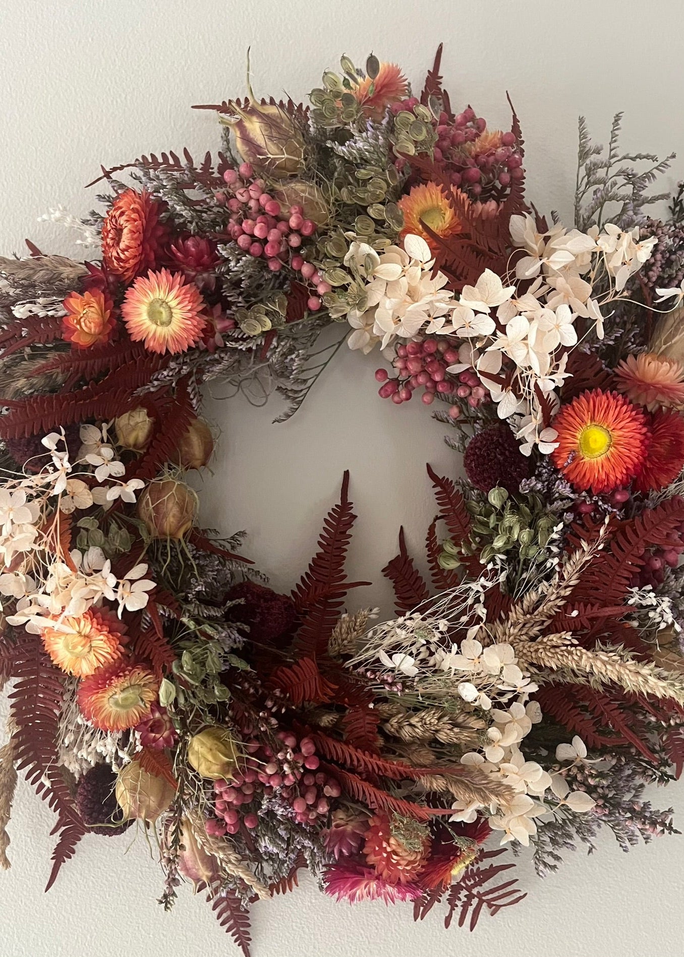 Decorative wreath with autumnal flowers and foliage on a white background