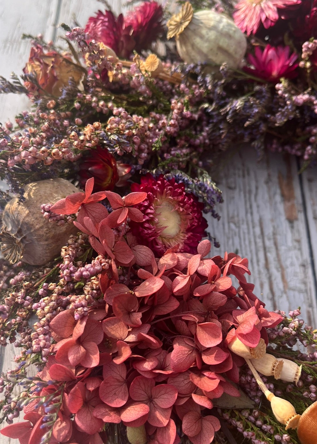 Floral wreath with pink and purple flowers on a wooden surface