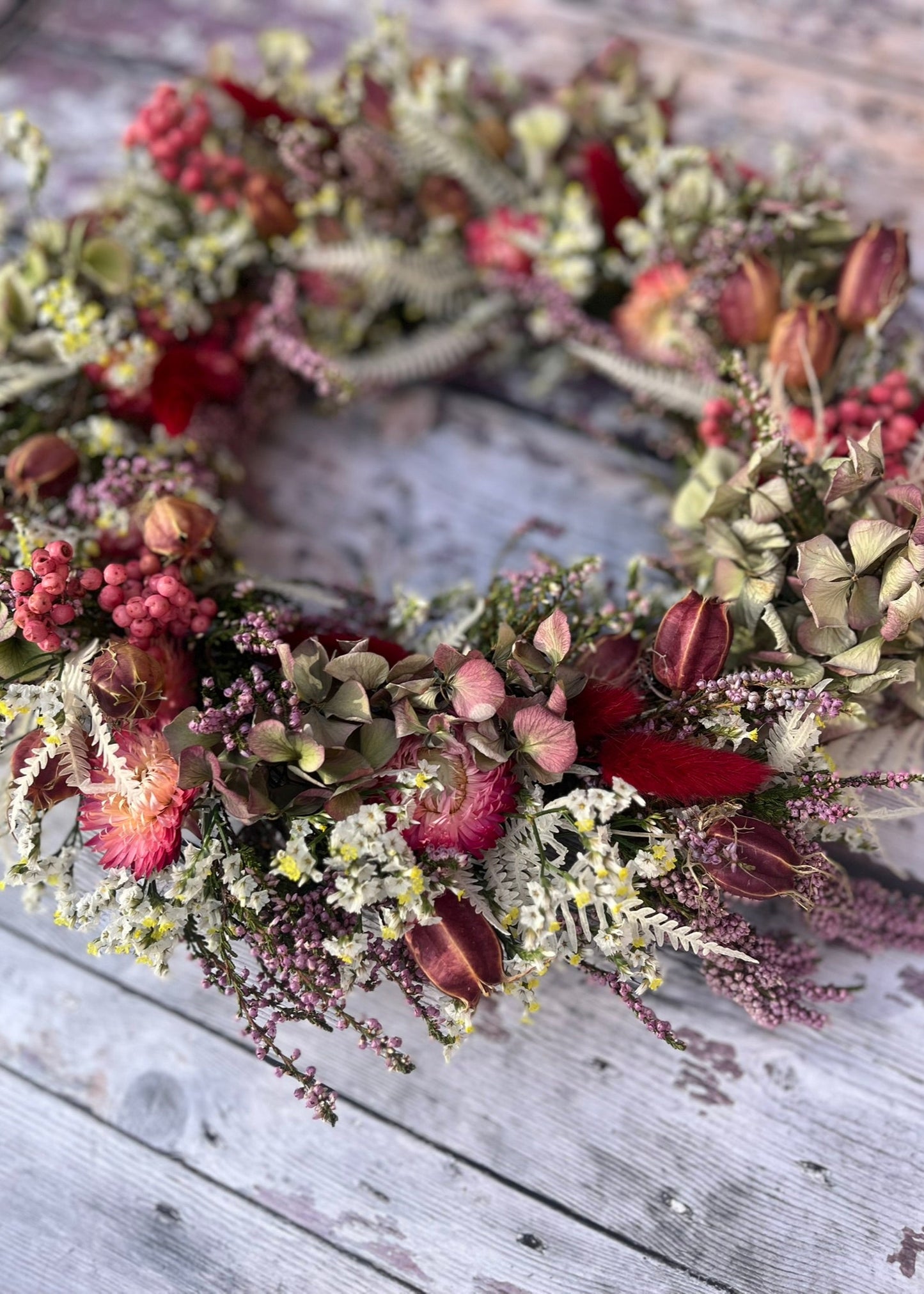 Floral wreath with red and green elements on a wooden surface