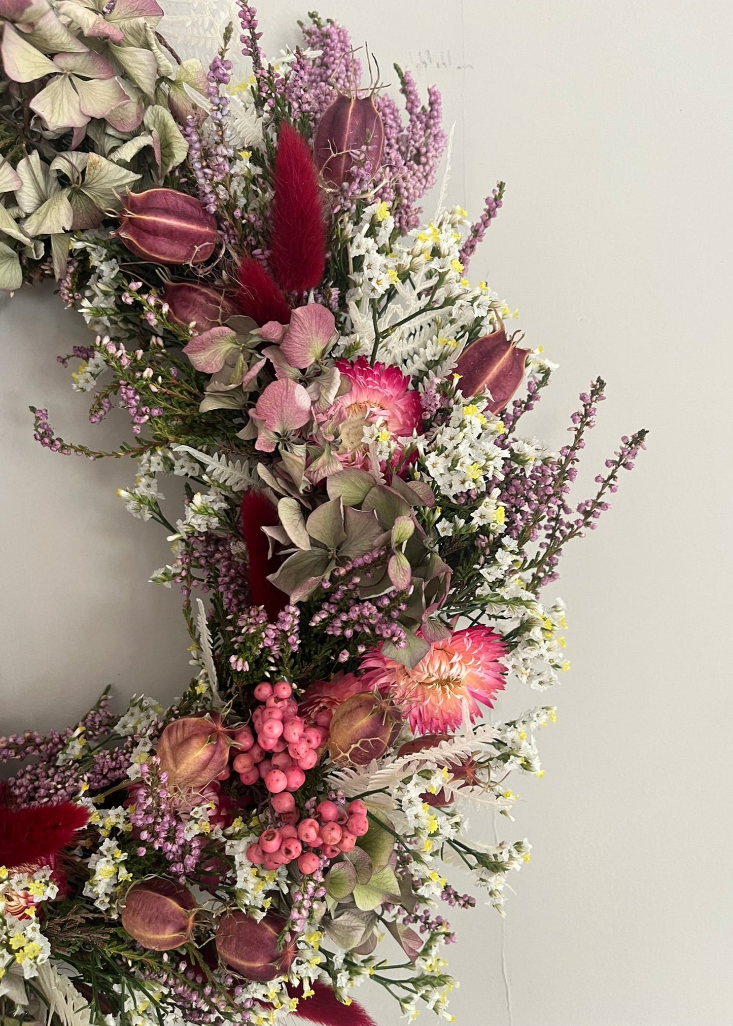 Floral wreath with a variety of flowers and leaves on a plain background