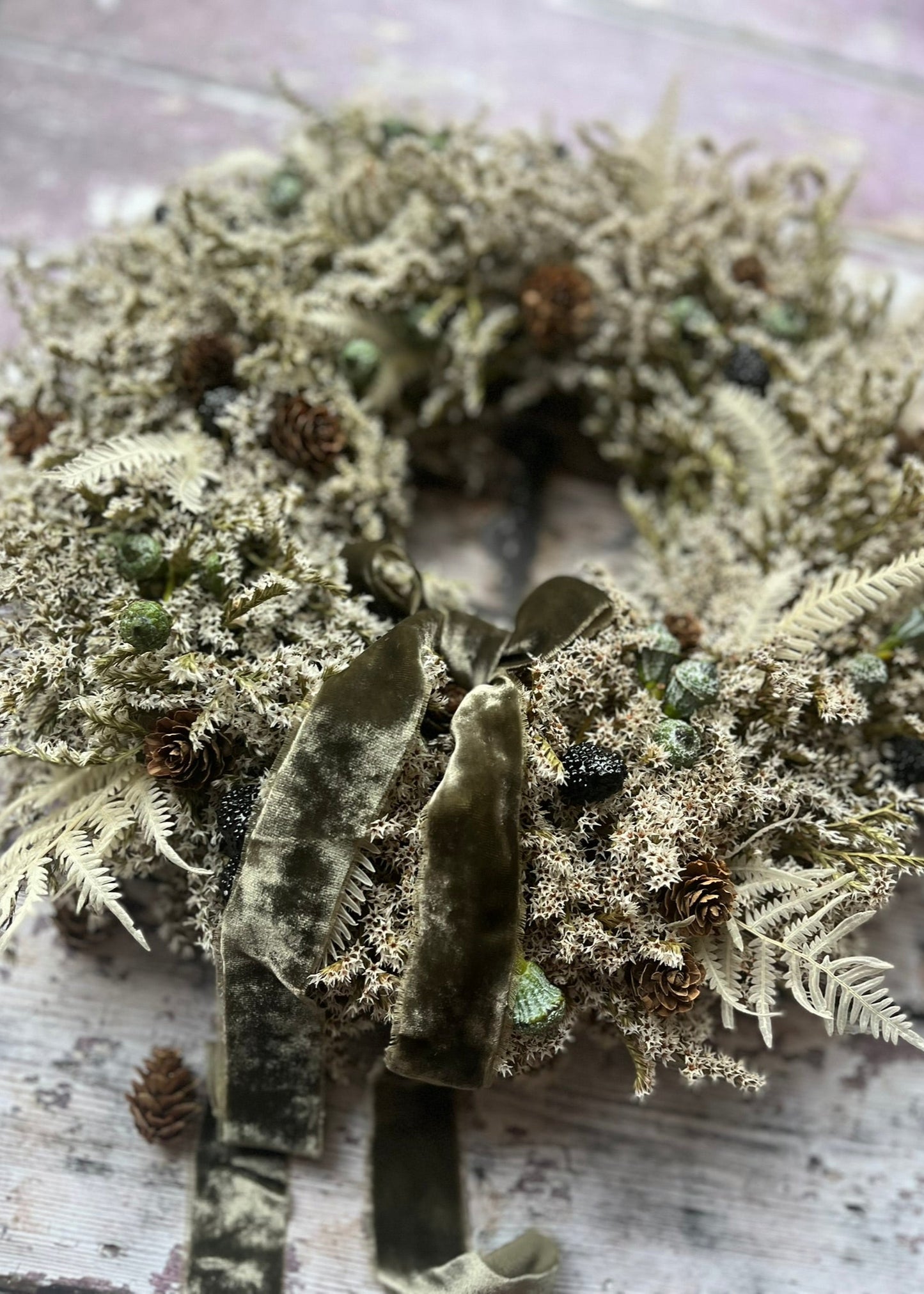 Wreath made of dried plants and moss on a wooden surface
