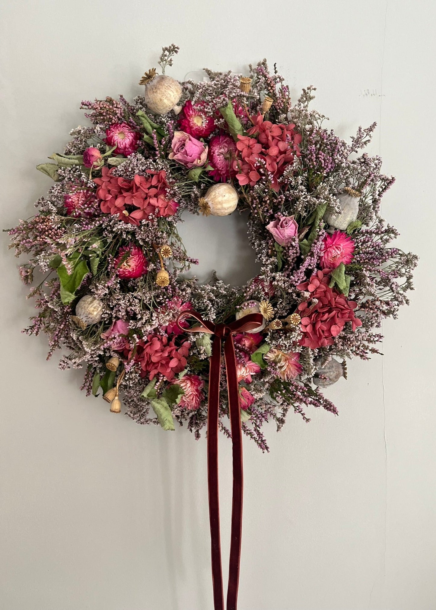 Decorative floral wreath with pink flowers and gold ornaments on a plain background