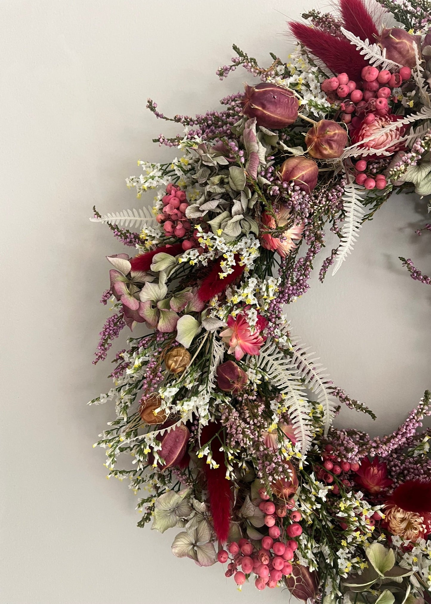 Floral wreath with pink and red flowers on a white wall