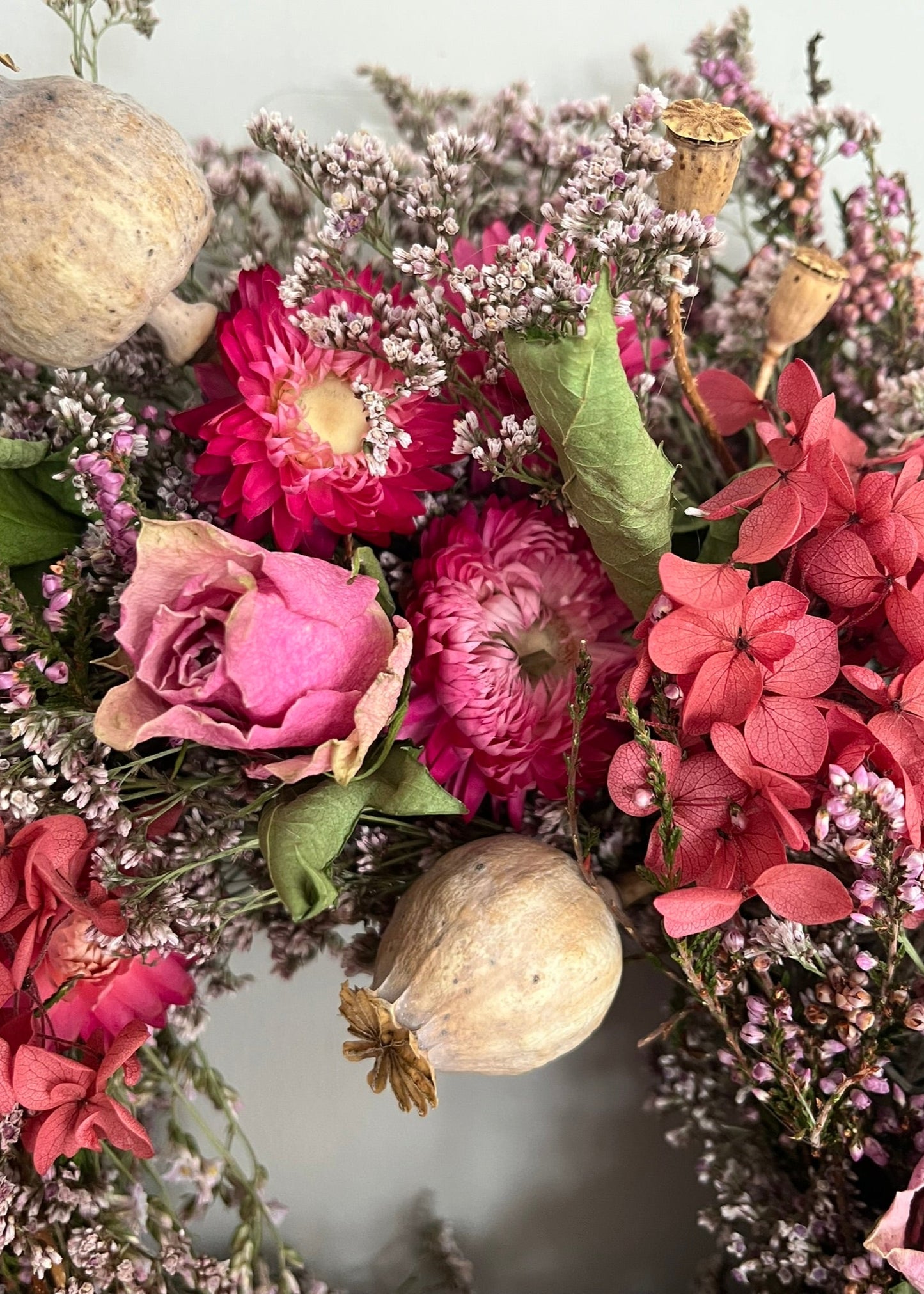 Close-up of a bouquet of pink and red flowers with green leaves.