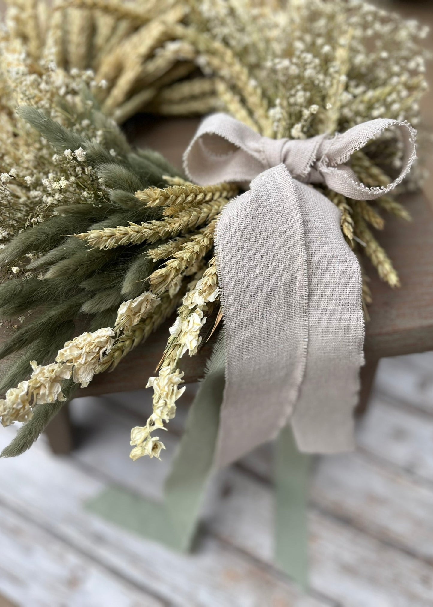 Decorative wreath with greenery and a ribbon on a wooden surface
