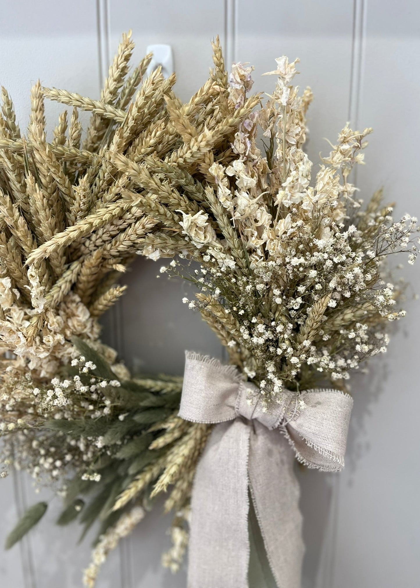 Wreath with dried grasses and white flowers on a gray background
