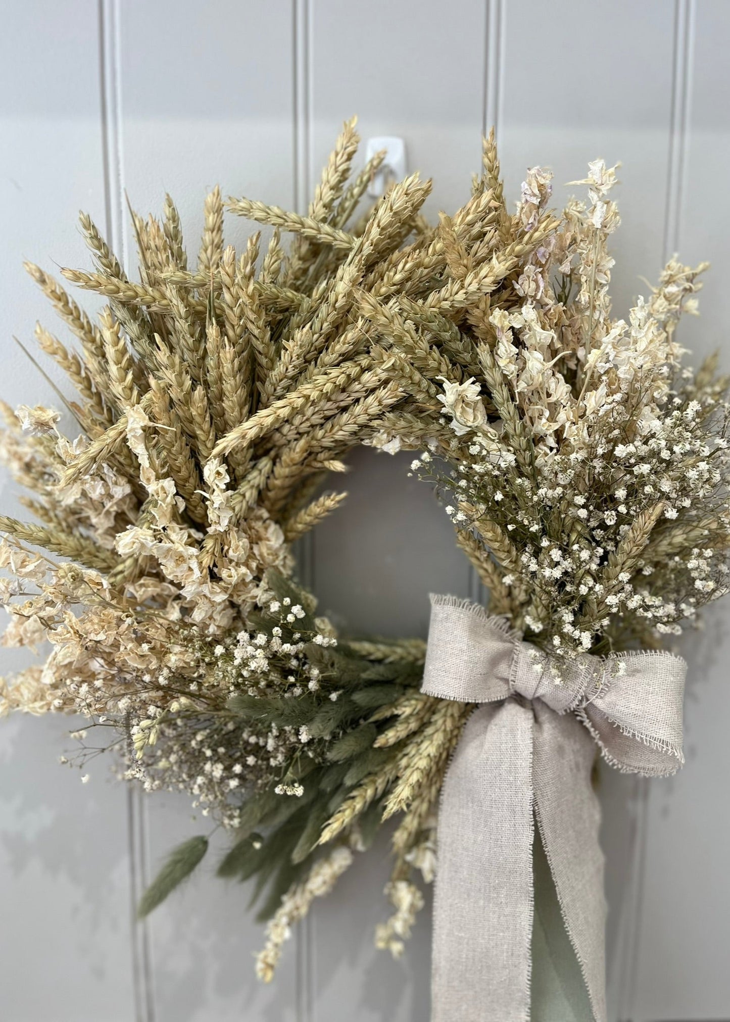 Wreath with dried grasses and a bow on a light gray background