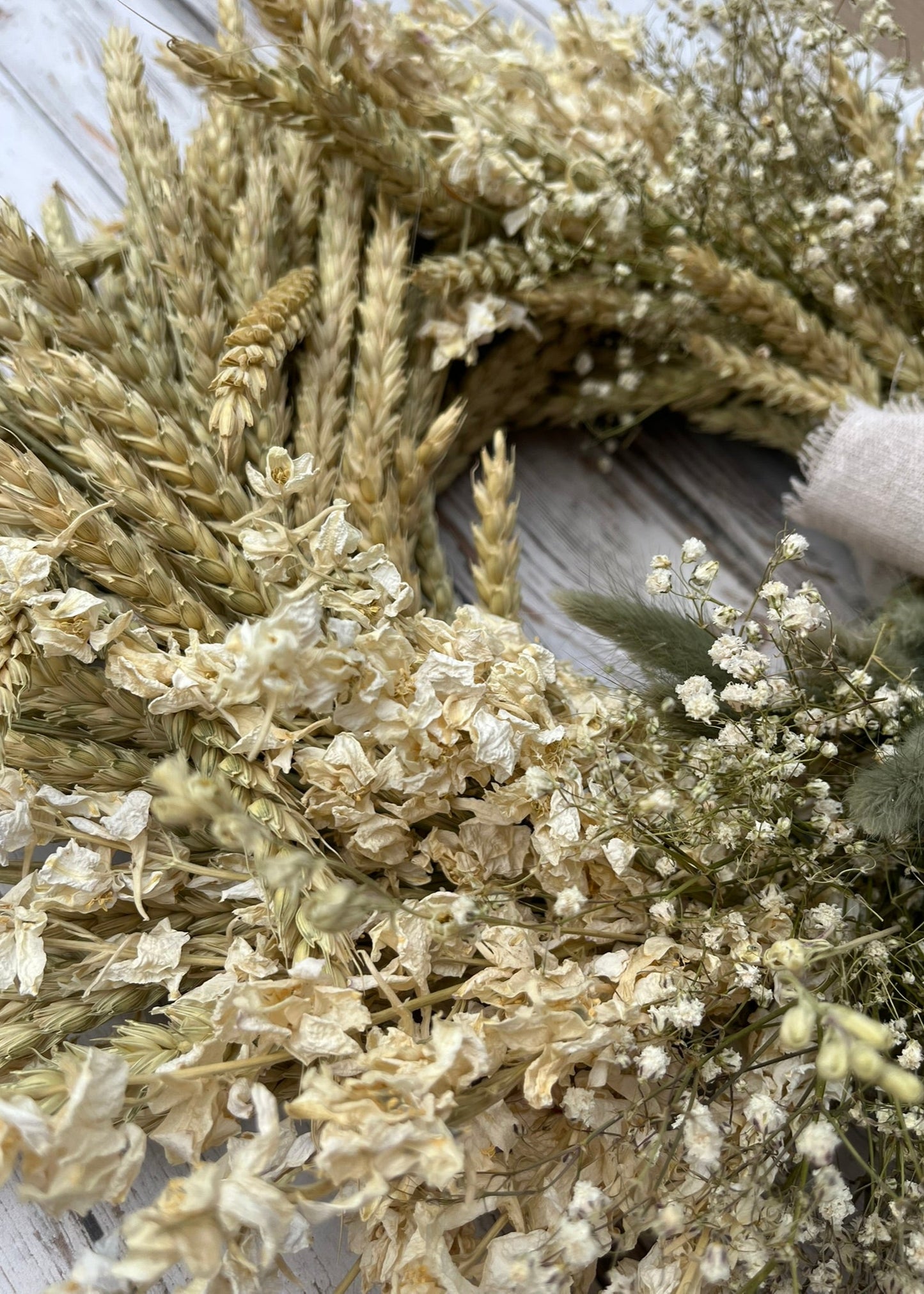 Wreath made of dried flowers and grasses on a wooden surface
