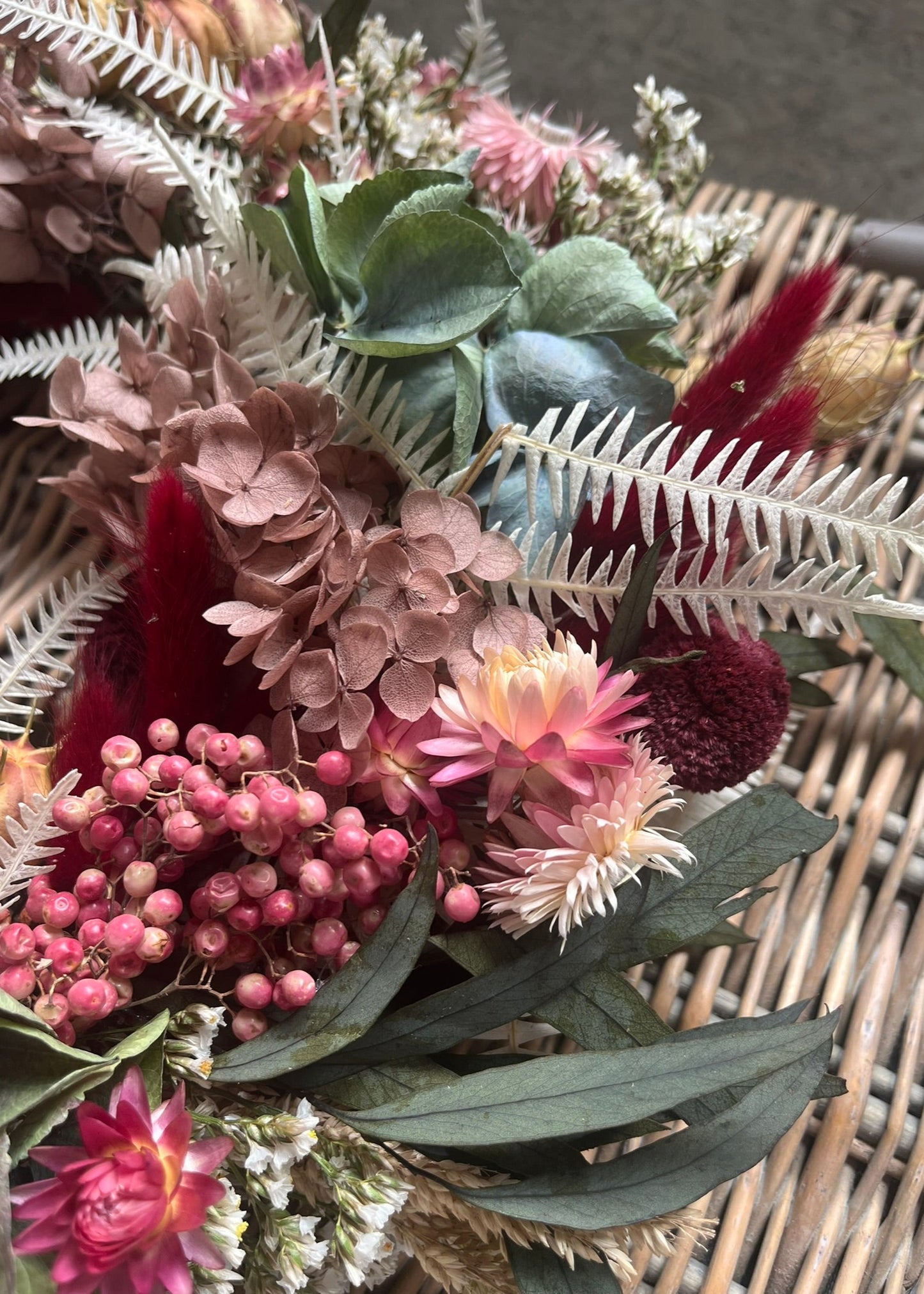Bouquet of dried flowers and greenery on a woven surface
