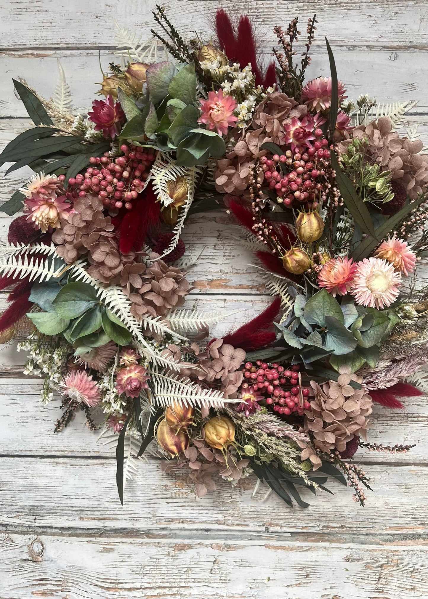 Floral wreath with pink and green flowers on a wooden background