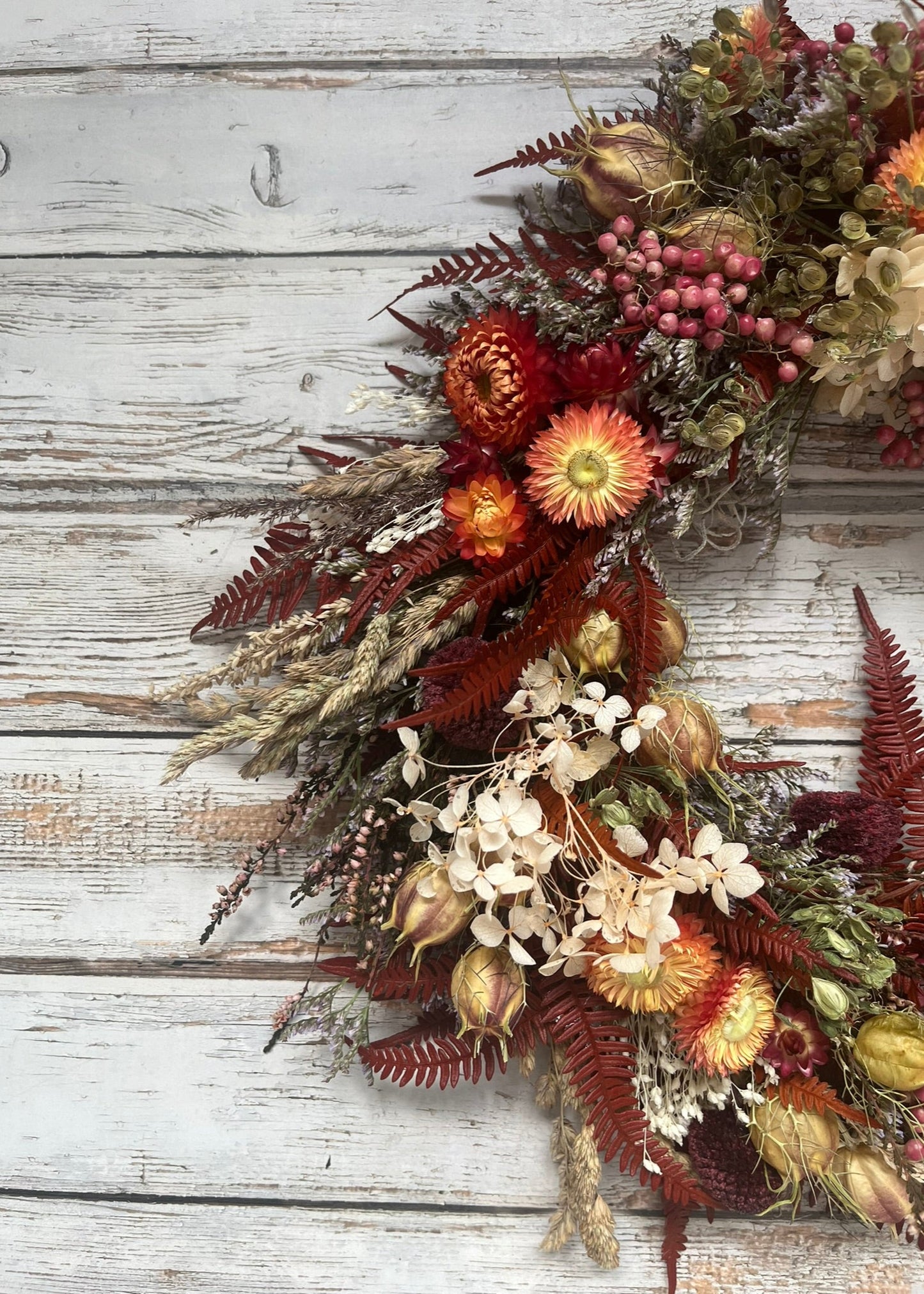 Decorative fall wreath with autumnal flowers and leaves on a wooden background
