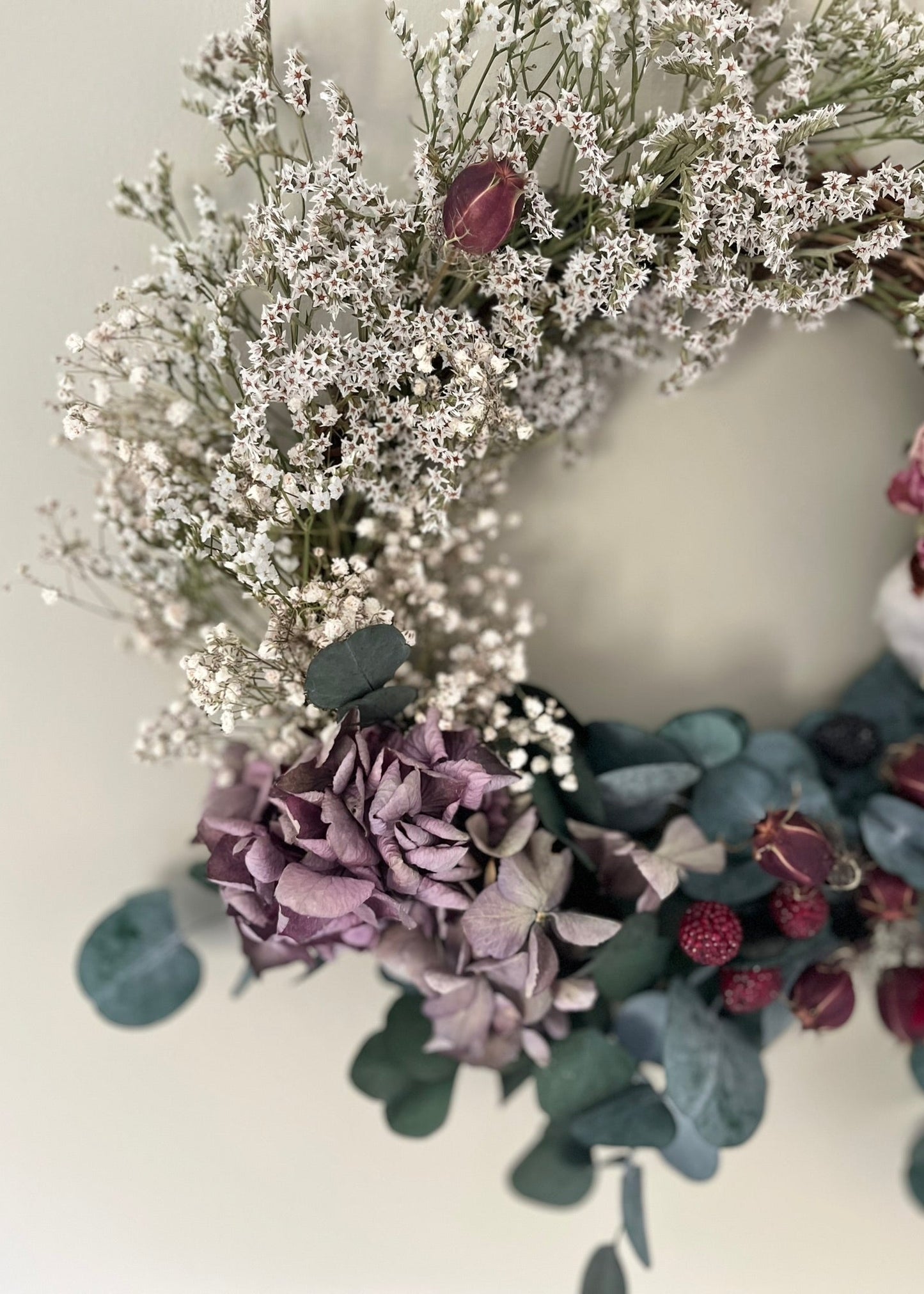 Floral wreath with white, purple, and green flowers on a light background