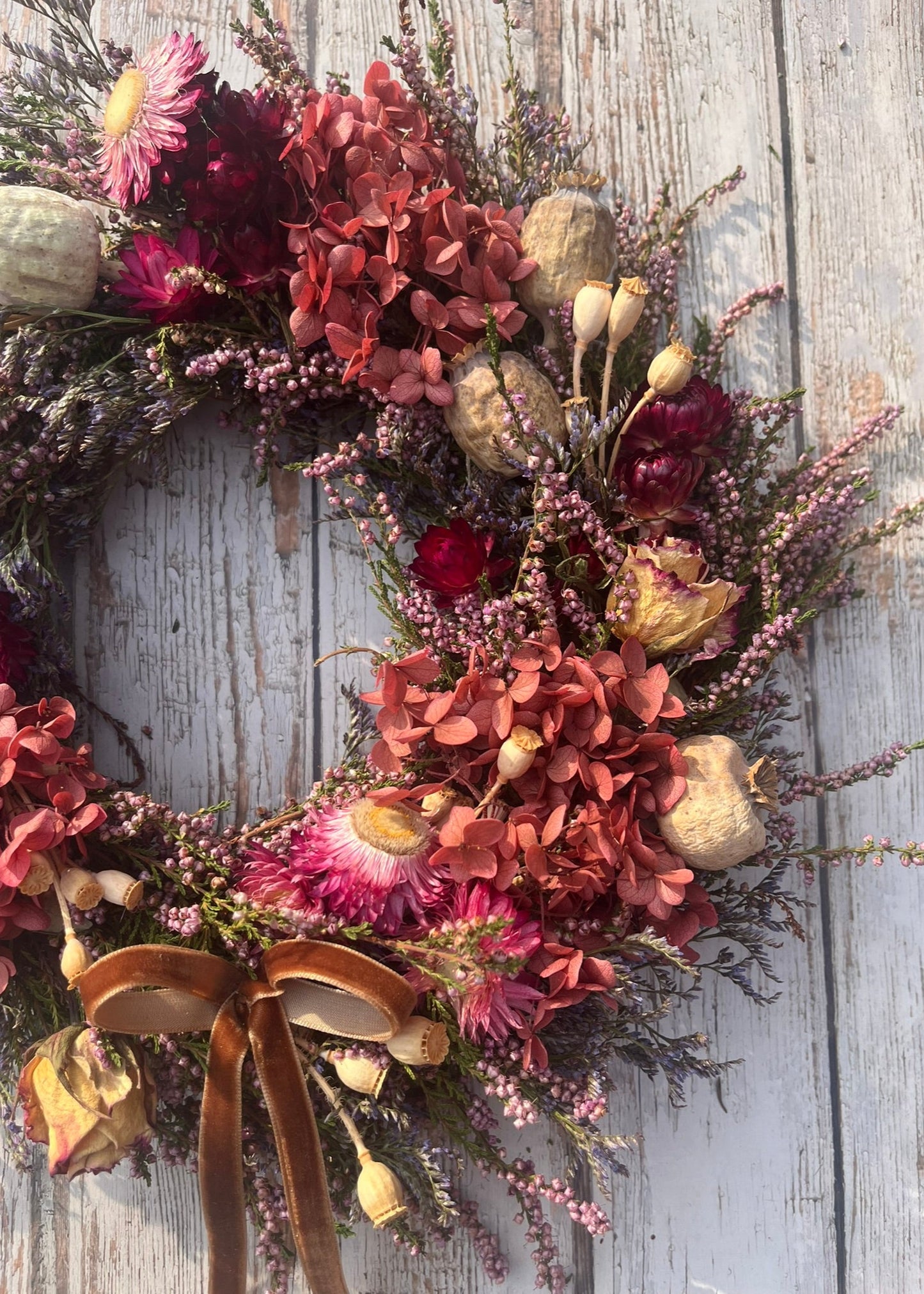 Decorative floral wreath with a brown ribbon on a wooden surface