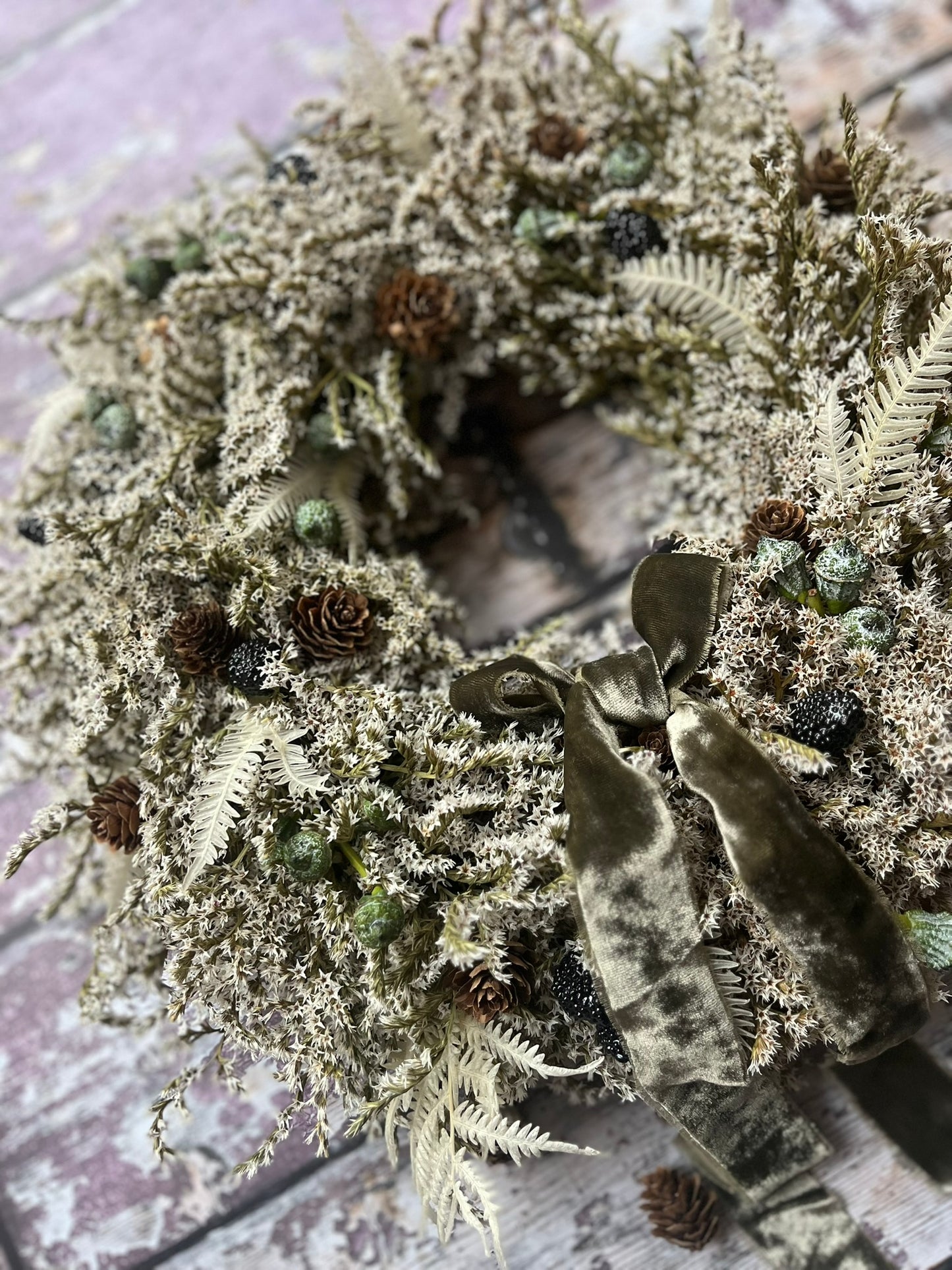 Decorative wreath with greenery and a bow on a textured surface