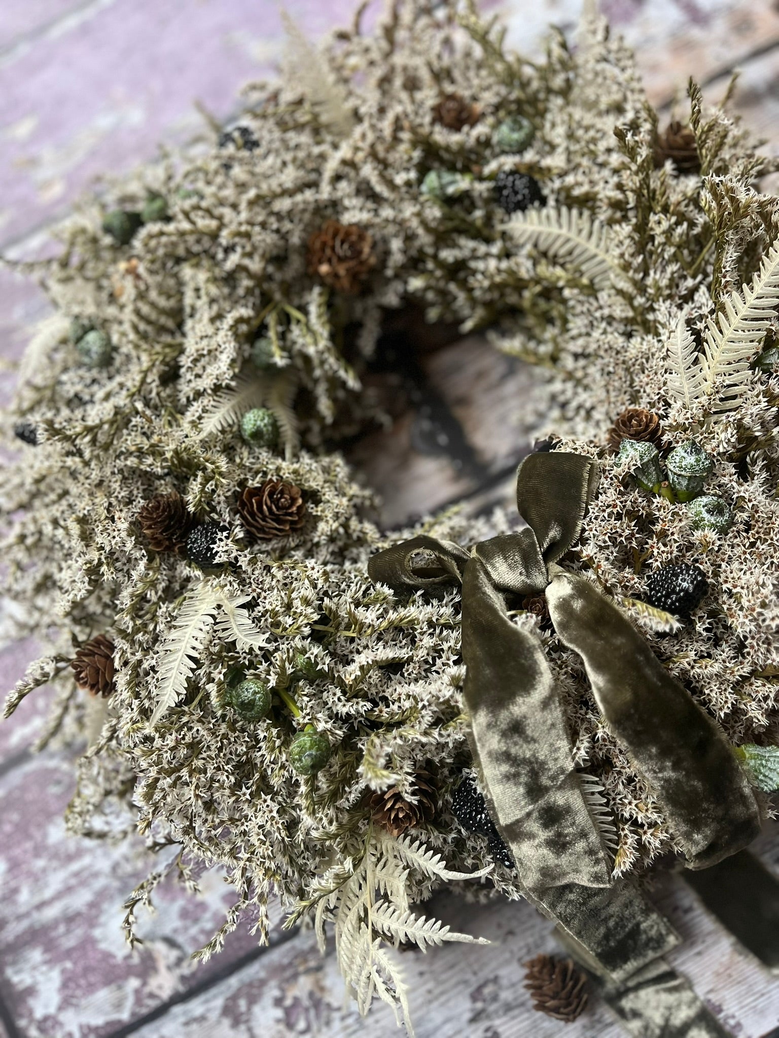Decorative wreath with greenery and a bow on a textured surface