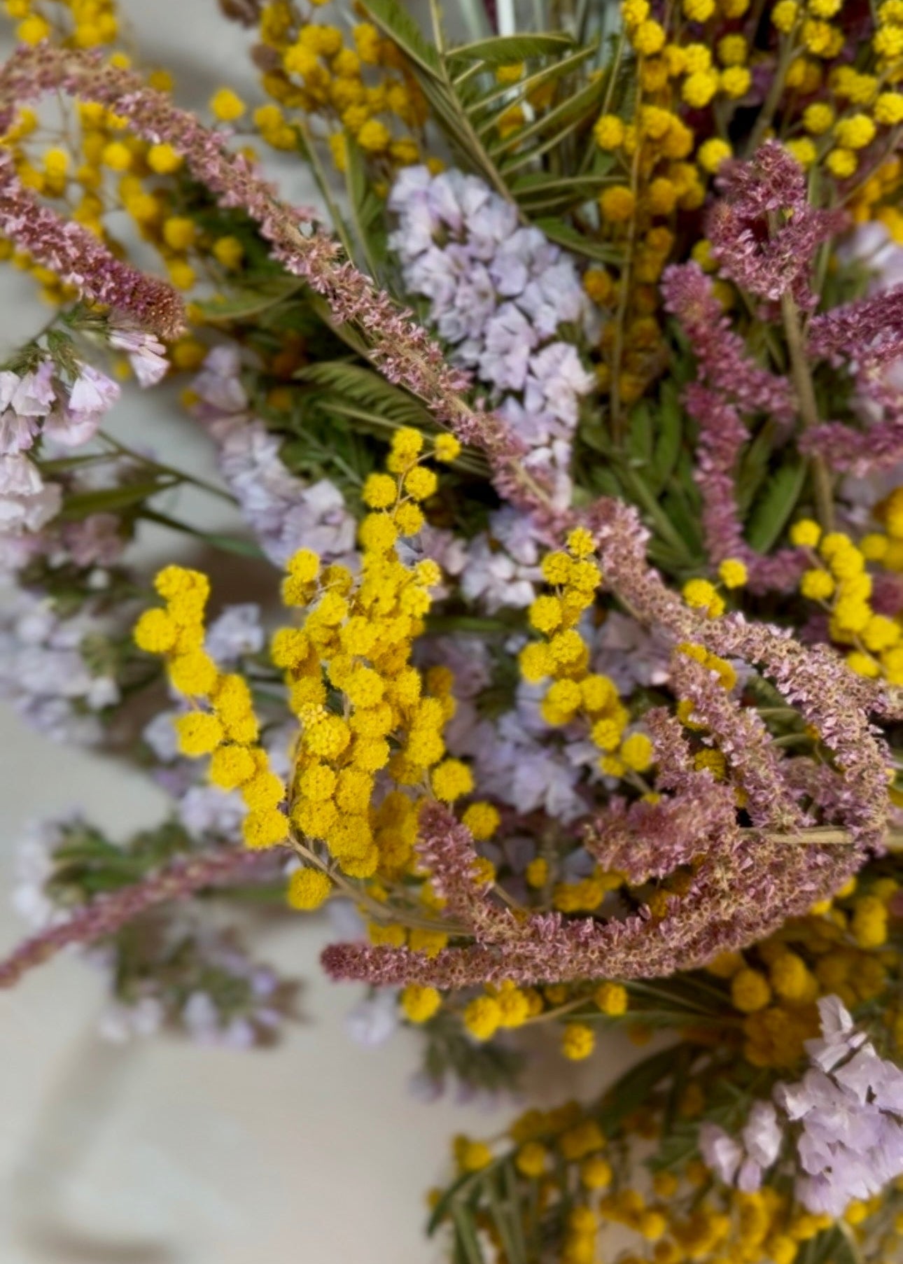 Close-up of a bouquet of flowers with yellow, pink, and green colors.