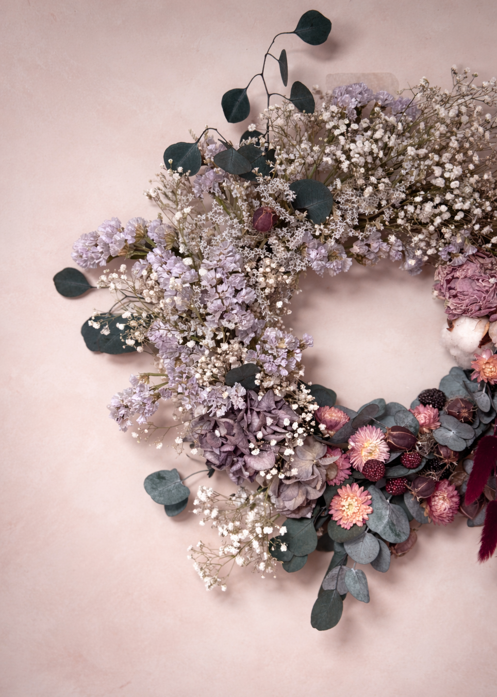 Floral wreath with purple and pink flowers on a light pink background