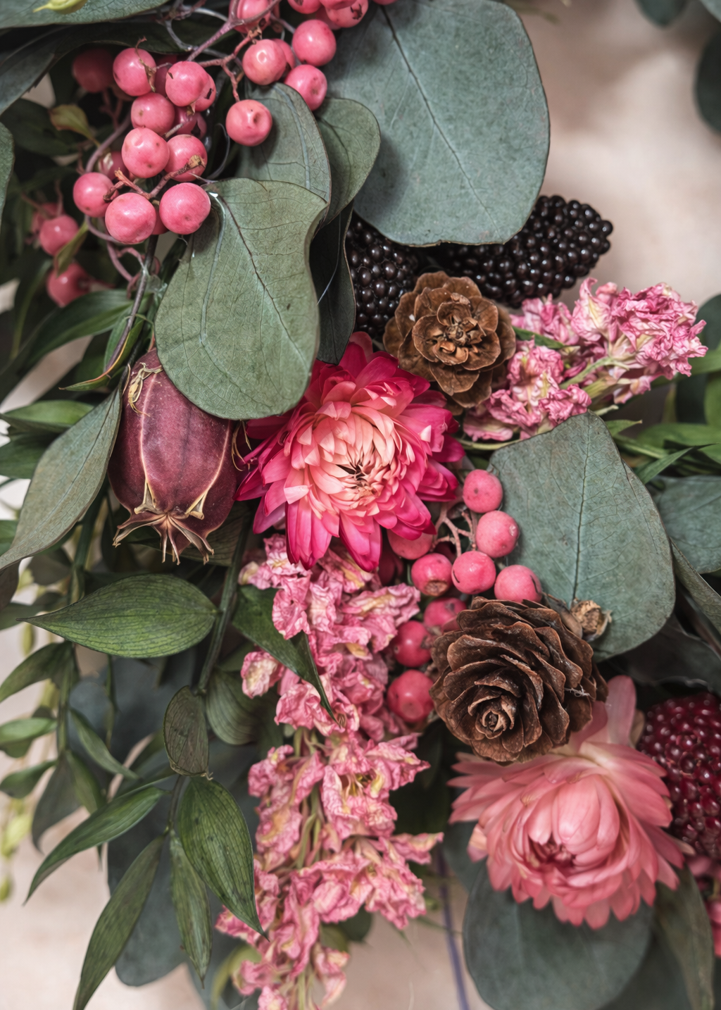 Close-up of a floral arrangement with pink flowers, green leaves, and berries.