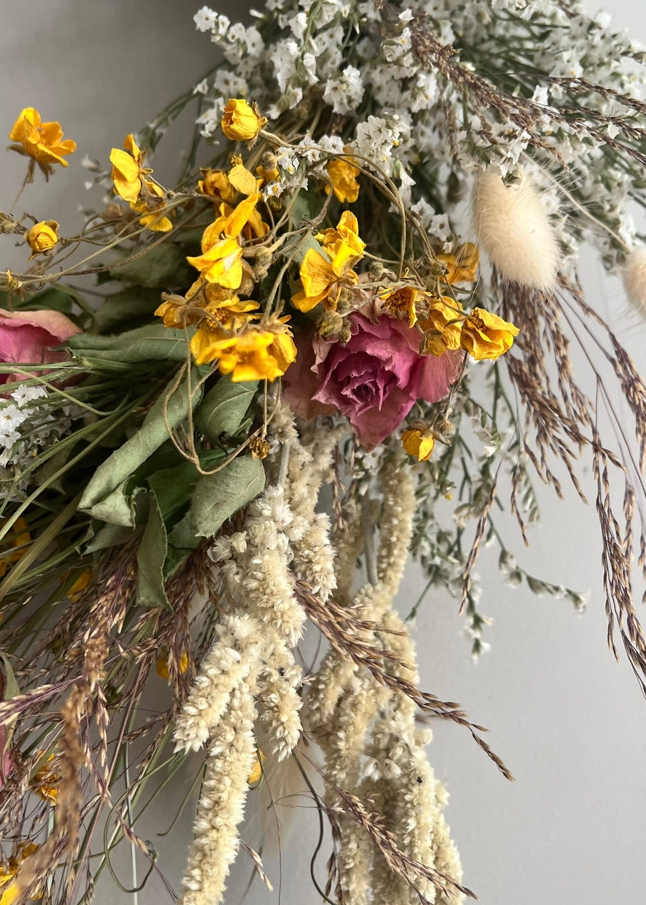 Dried flowers and herbs with yellow, pink, and green colors on a neutral background