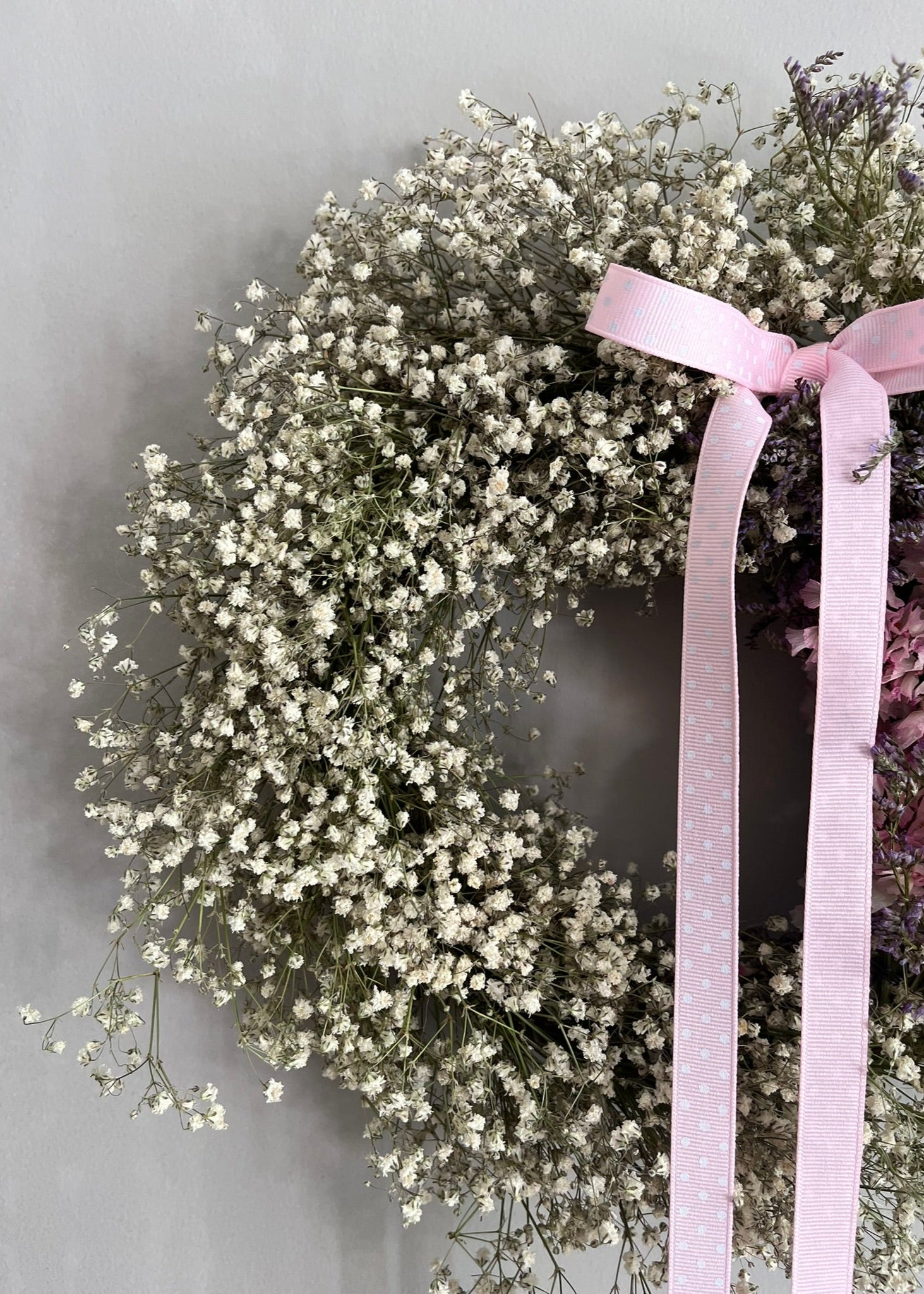 A pretty pink and white dried flower wreath with gypsophila—fresh from our spring range, full of soft textures and seasonal charm, with a polka dot bow at the top.