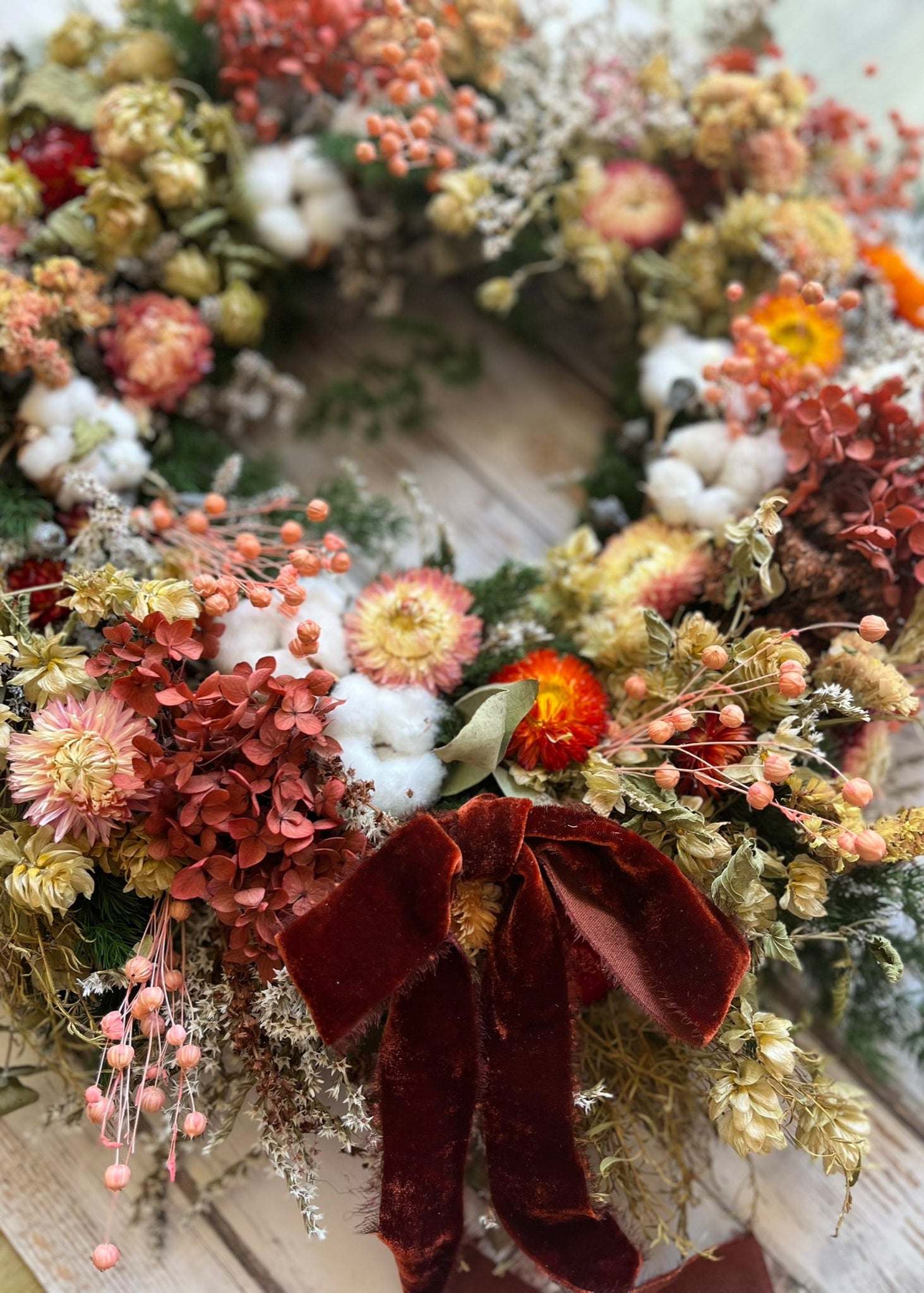 Peach dried flower wreath with terracotta hydrangea, peach berries, helichrysum, green hops, white statice, large wild natural wreath withscented eucalyptus with a hand torn rustic burnt orange ribbon bow at the bottom centre of grapevine base.