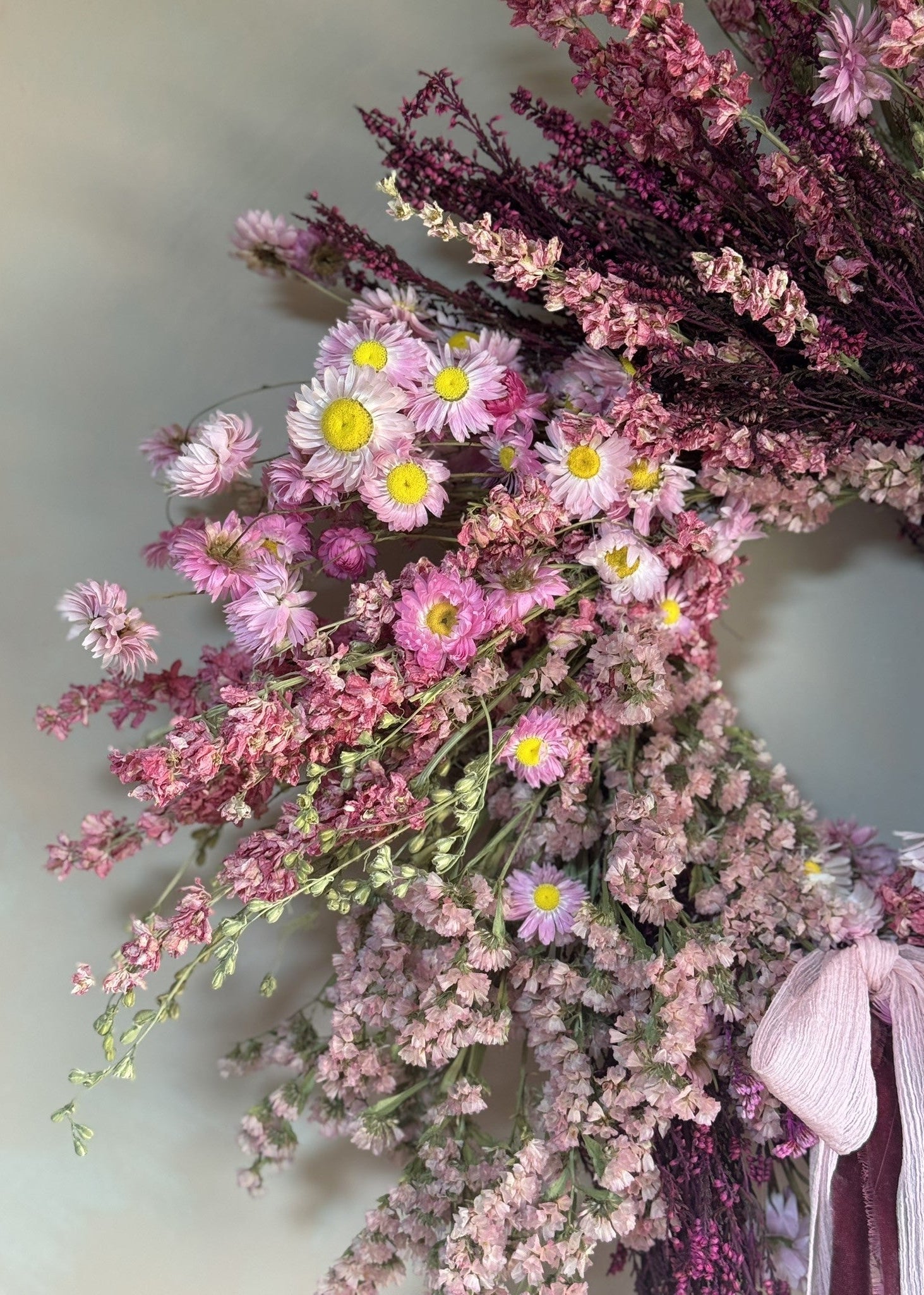 Bouquet of pink and purple flowers with green leaves against a light background