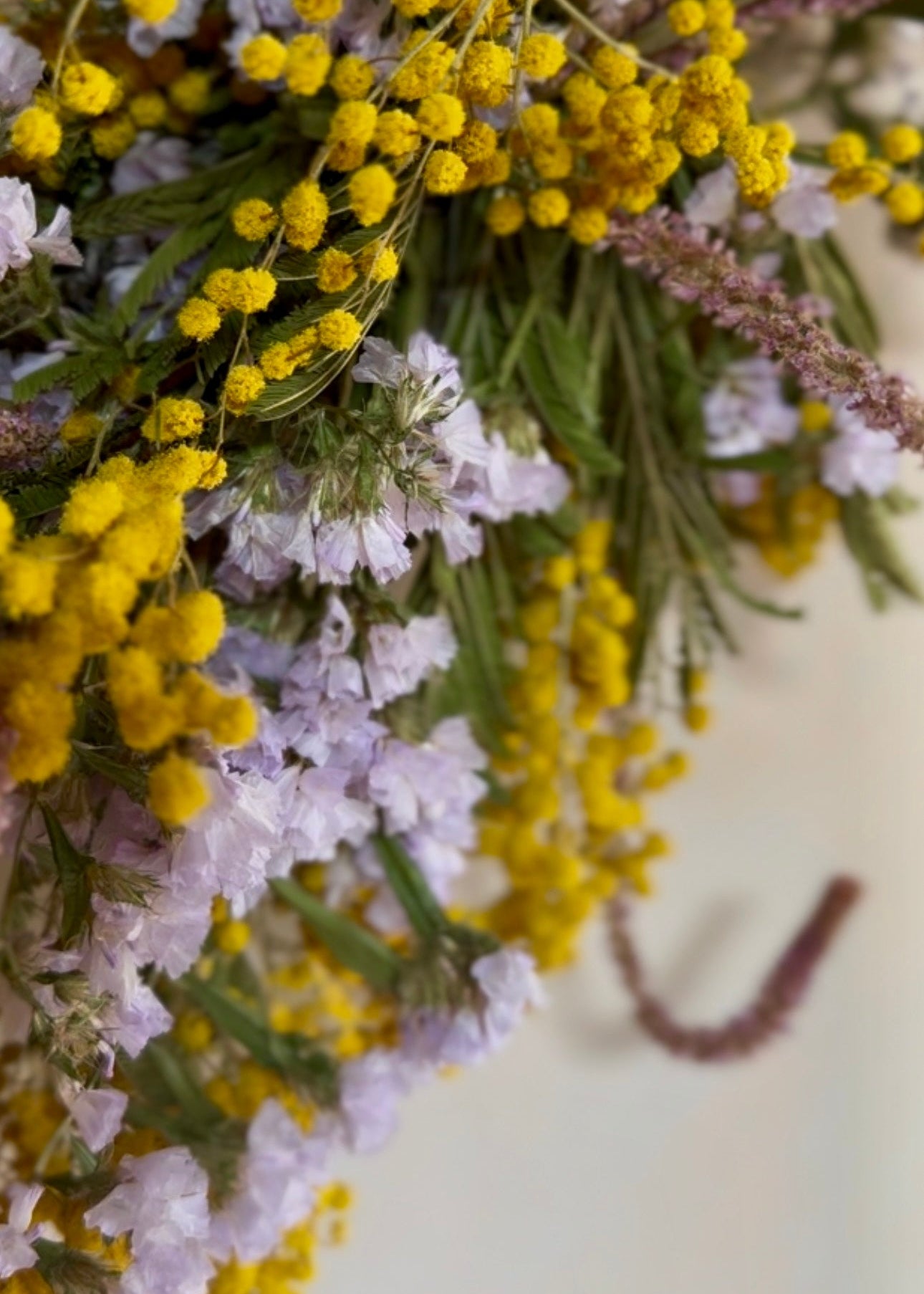 Close-up of a bouquet of yellow and white flowers with green leaves.