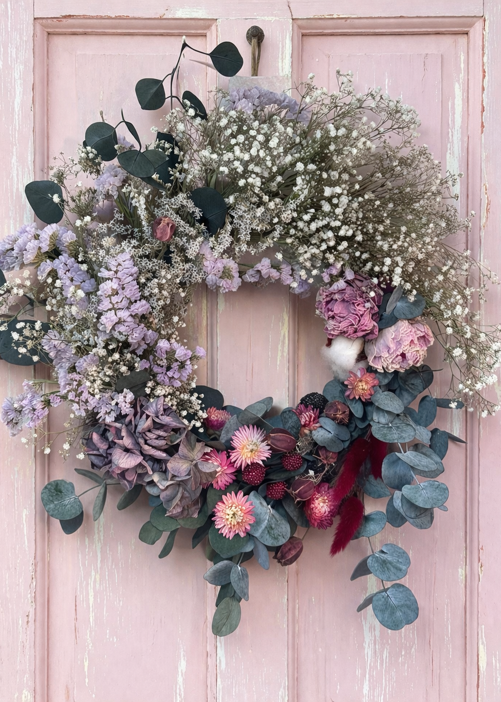 Three floral wreaths on a pink door