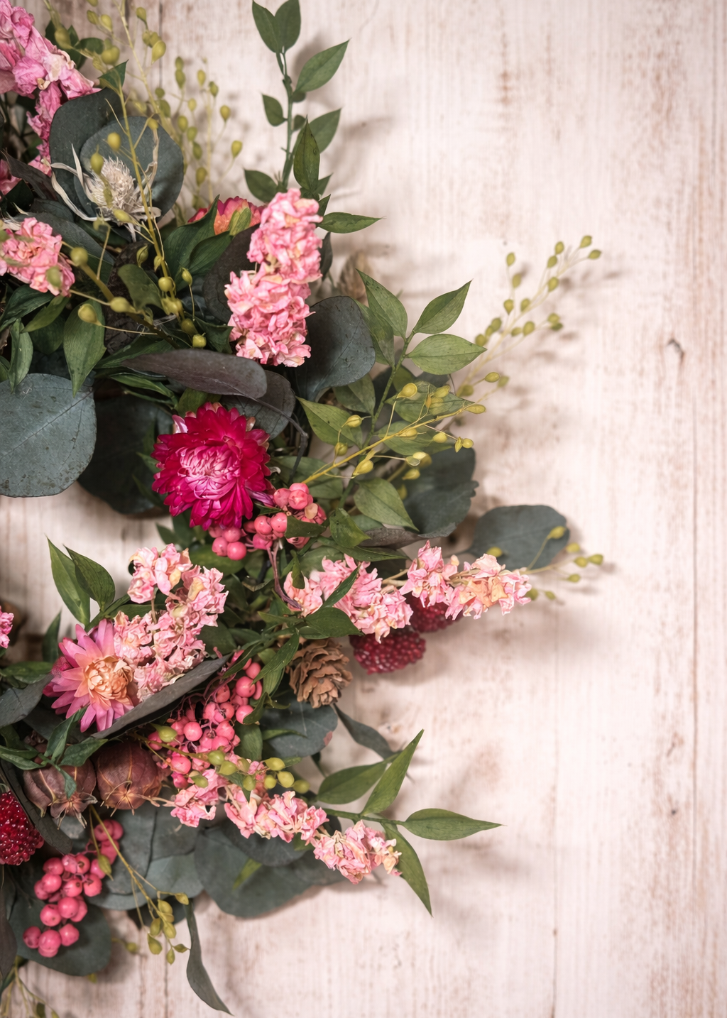 Floral wreath with pink and red flowers on a wooden background