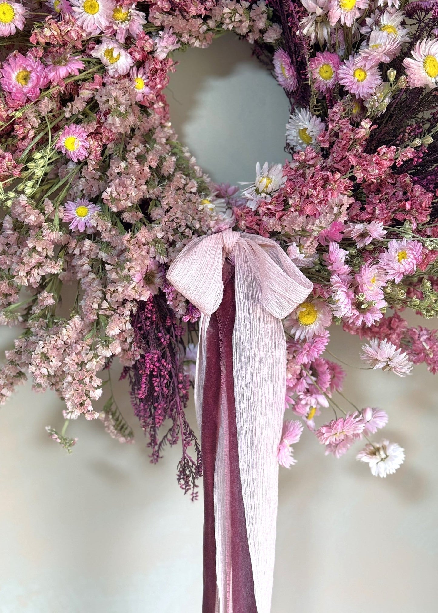 Floral wreath with pink flowers and a ribbon on a white background