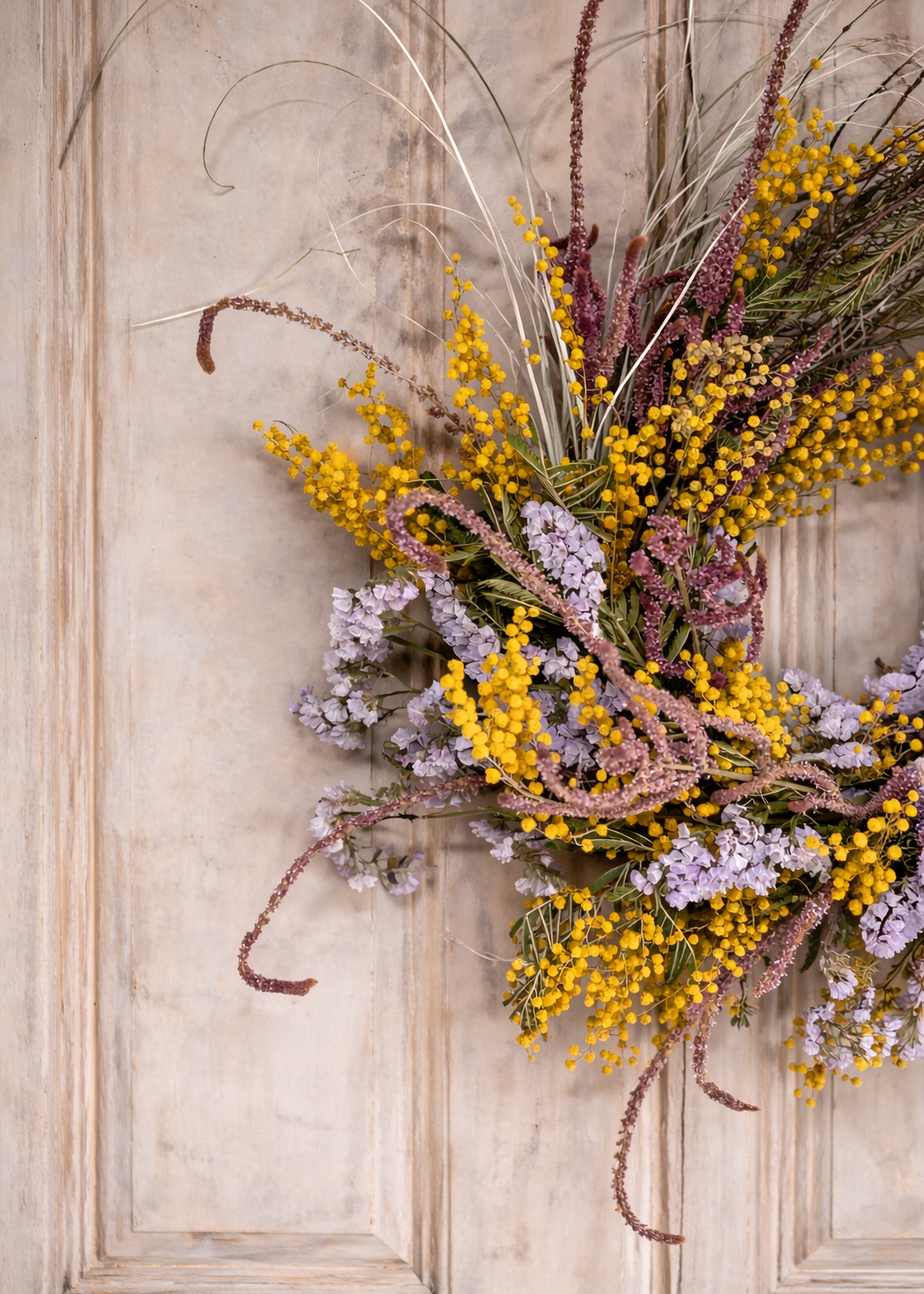 Decorative wreath with flowers and branches on a wooden door