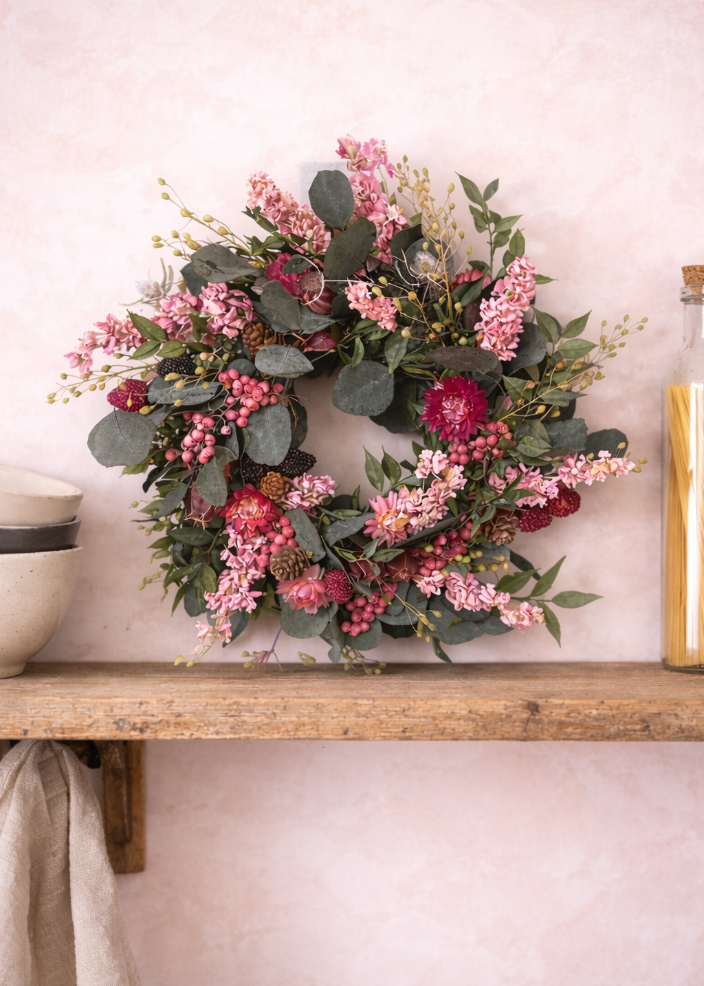 Floral wreath on a wooden shelf against a light wall