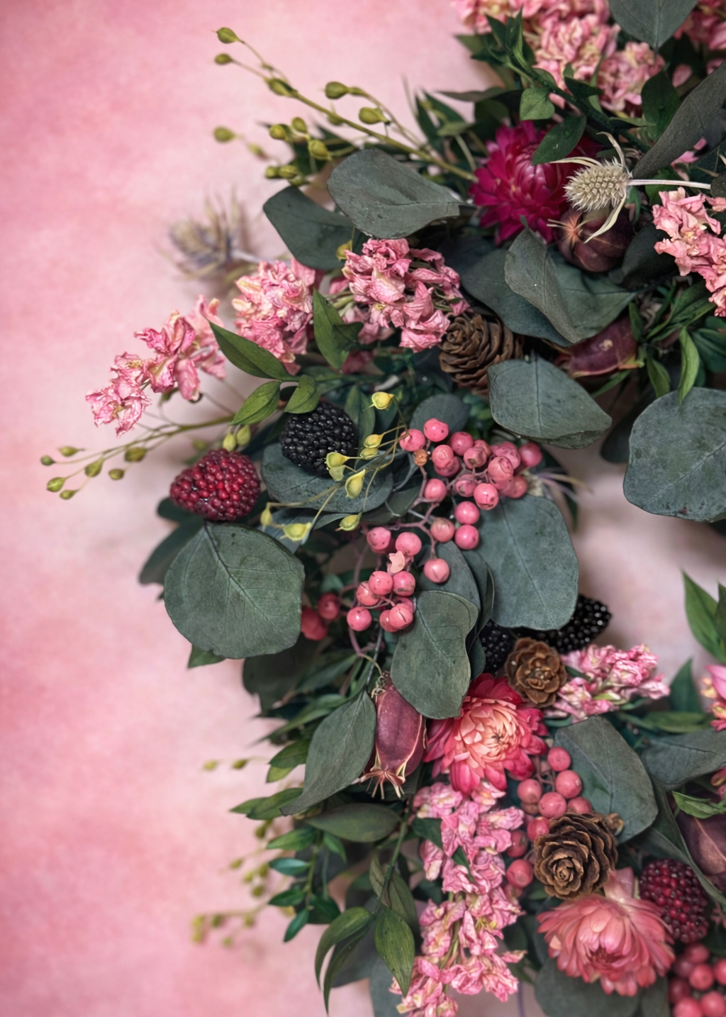 Floral arrangement with pink flowers and green leaves on a pink background