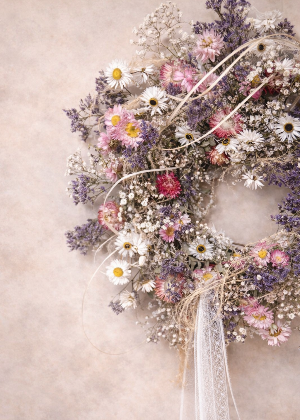 Elegant dried flower wreath in pastel tones, combining eucalyptus greenery with delicate white daisies and pink and purple gyp.