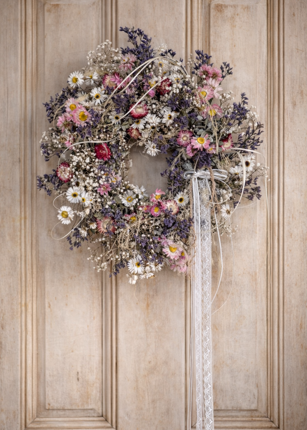 Spring-inspired dried wreath with soft pink, purple and white florals, featuring textured eucalyptus leaves, daisy flowers and fine gypsophila.