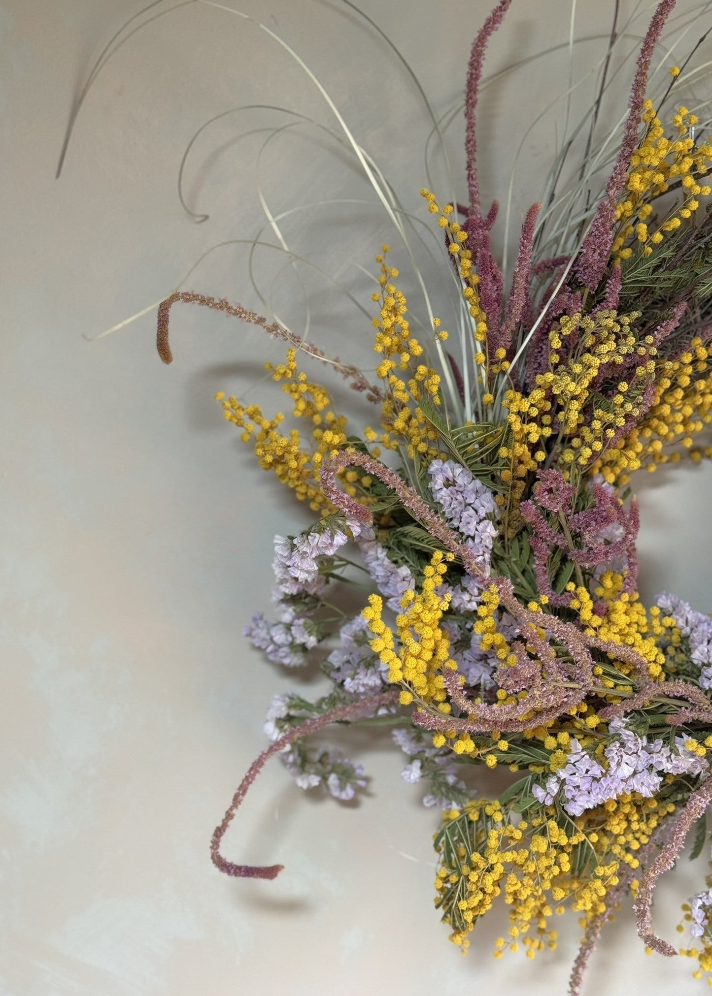 Decorative wreath with flowers and grasses on a plain background