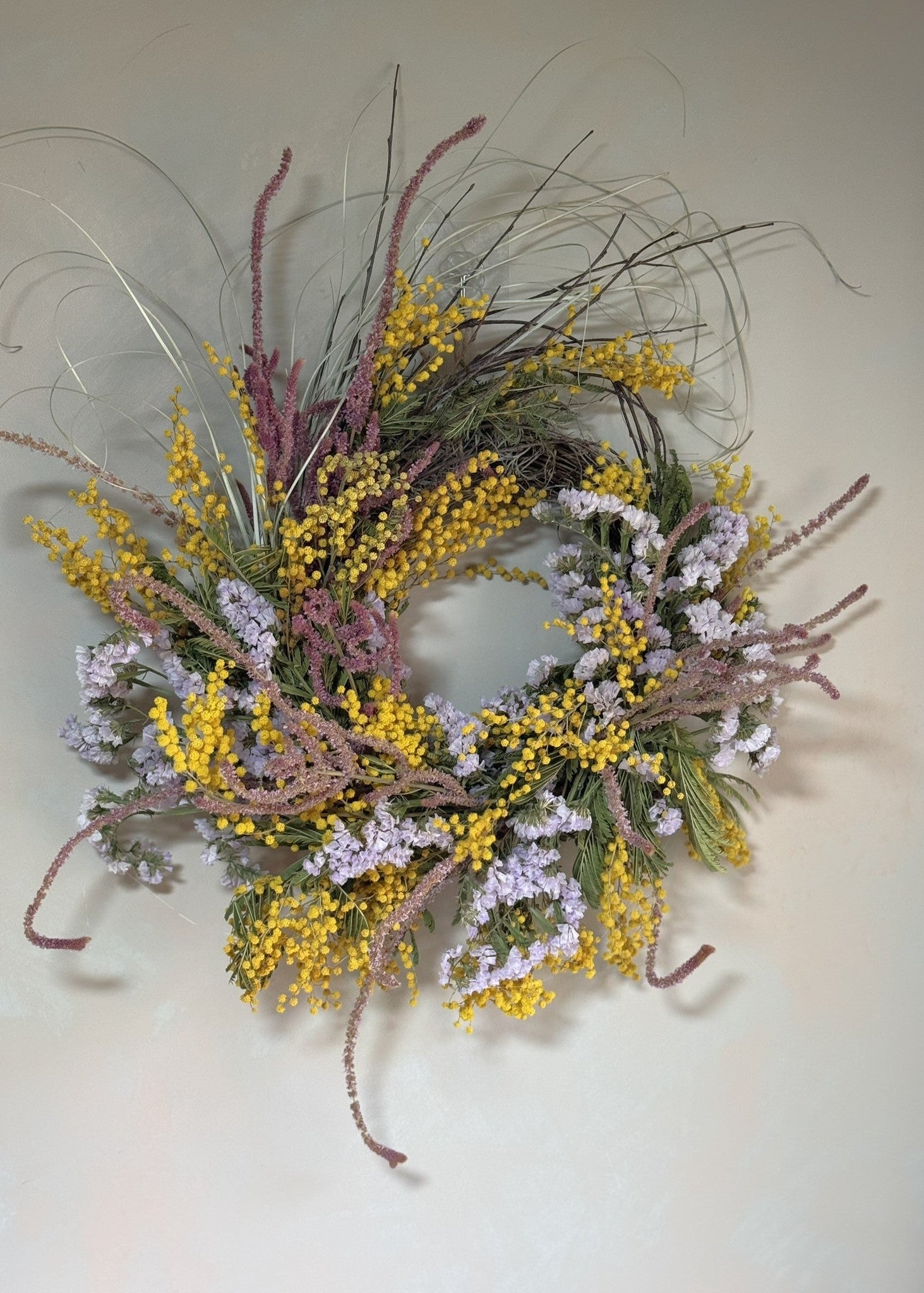 Decorative wreath with yellow and purple flowers on a plain background