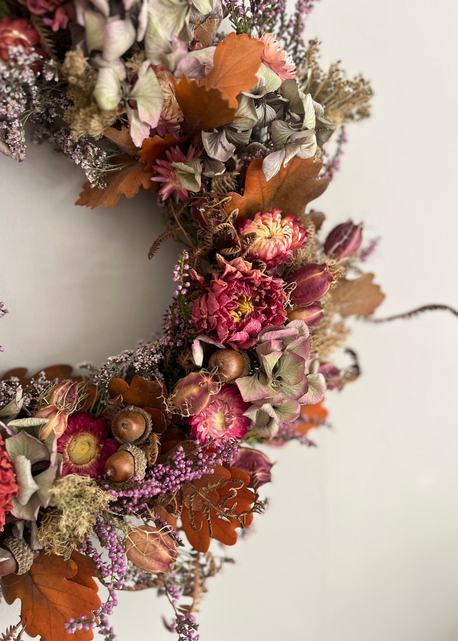 Autumn-themed floral wreath with dried flowers and leaves on a white background