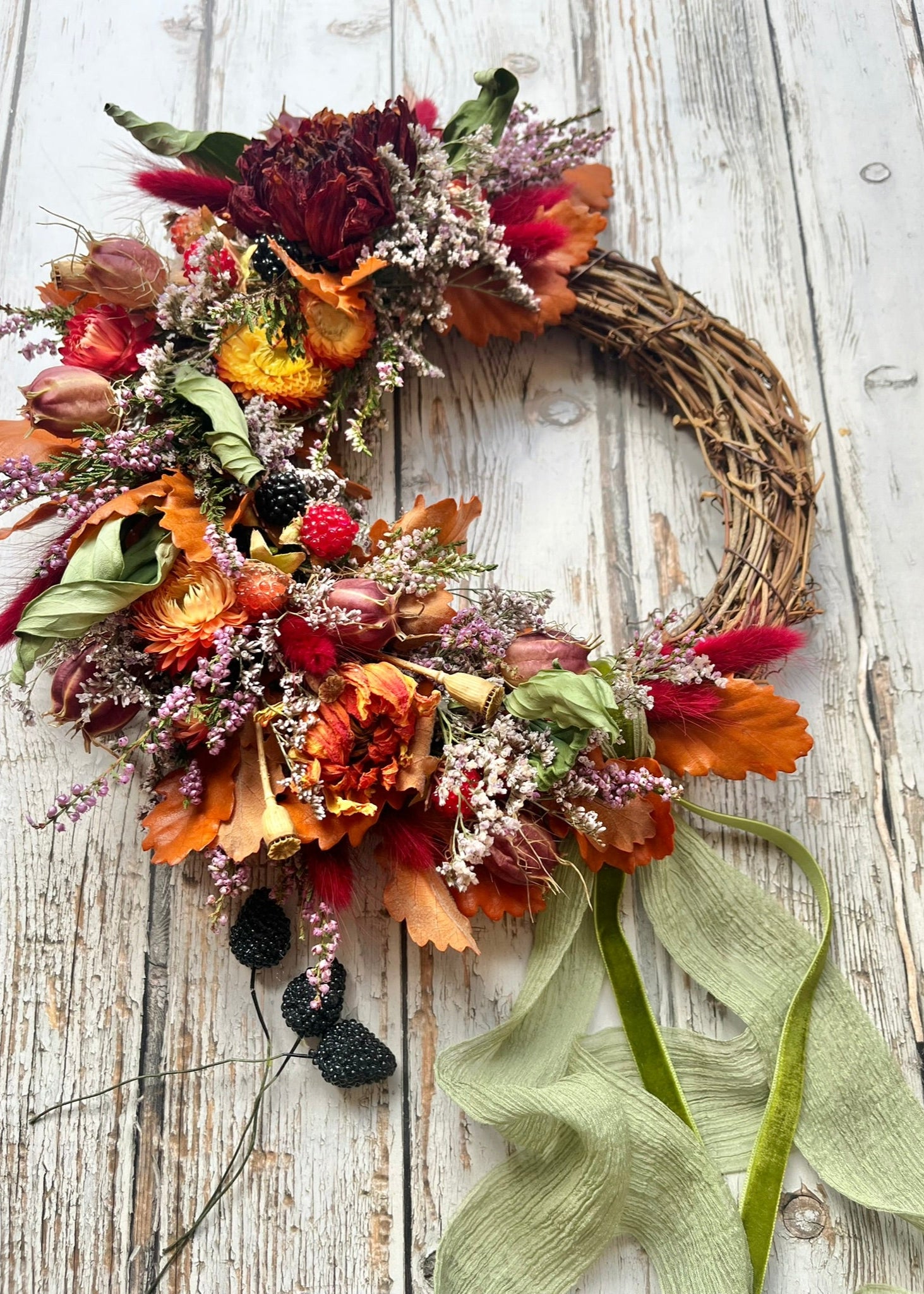 Autumn-themed wreath with colorful flowers and leaves on a wooden background