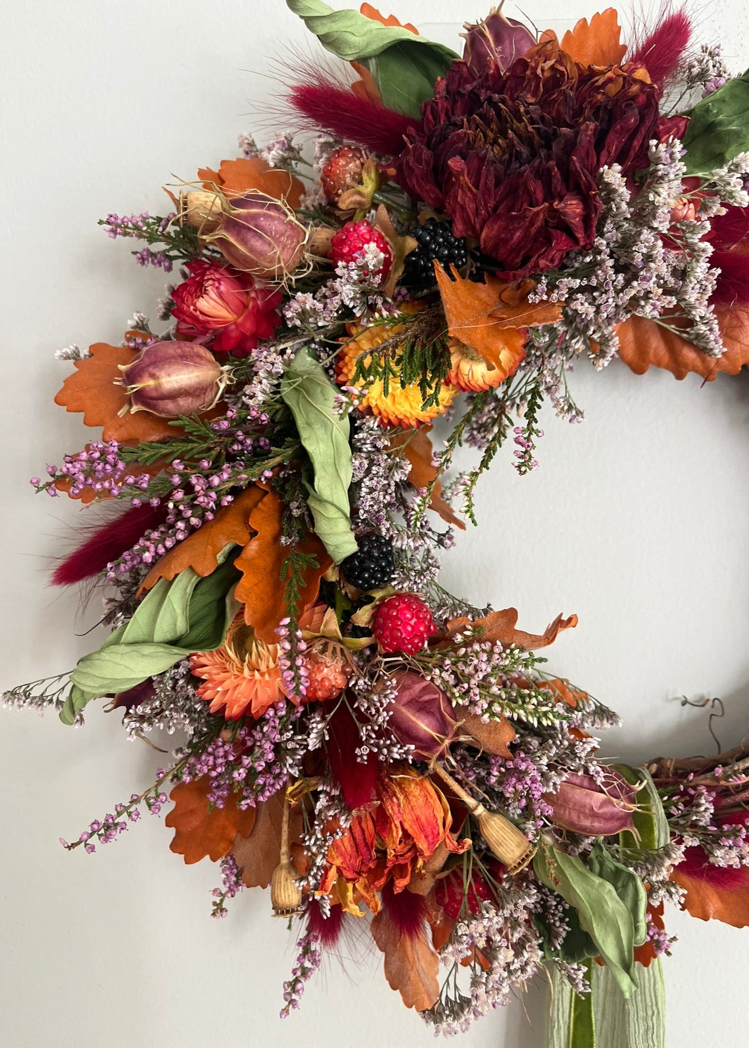 Autumn-themed wreath with colorful leaves and flowers on a white background