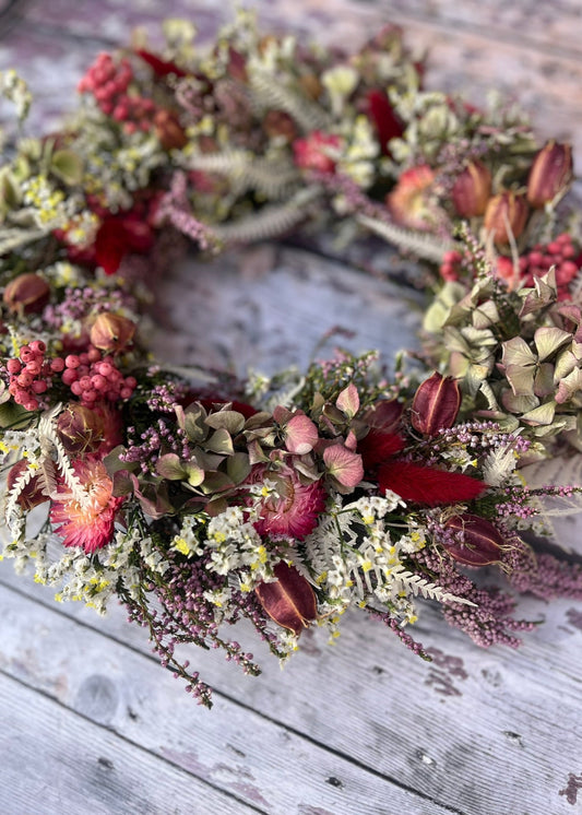 Floral wreath with red and green elements on a wooden surface