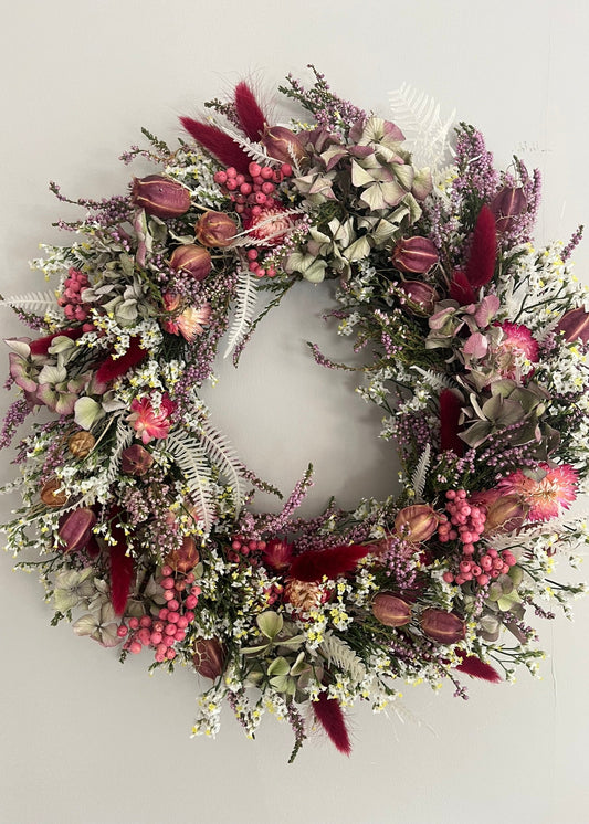 pretty autumnal dried flower wreath in shades of burgundy, red, green, white for a wall or door