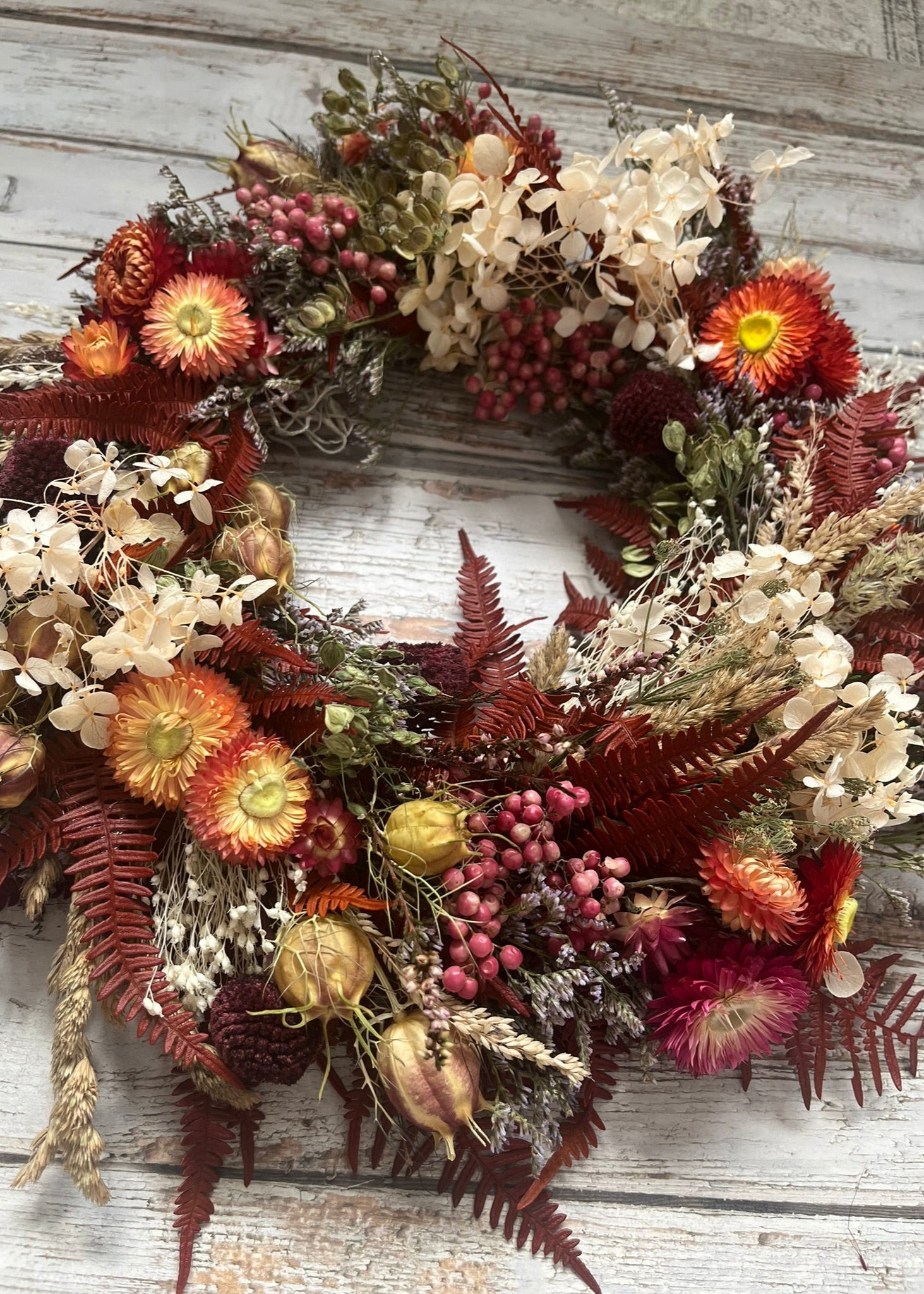 Autumnal wreath with dried flowers and berries on a wooden background