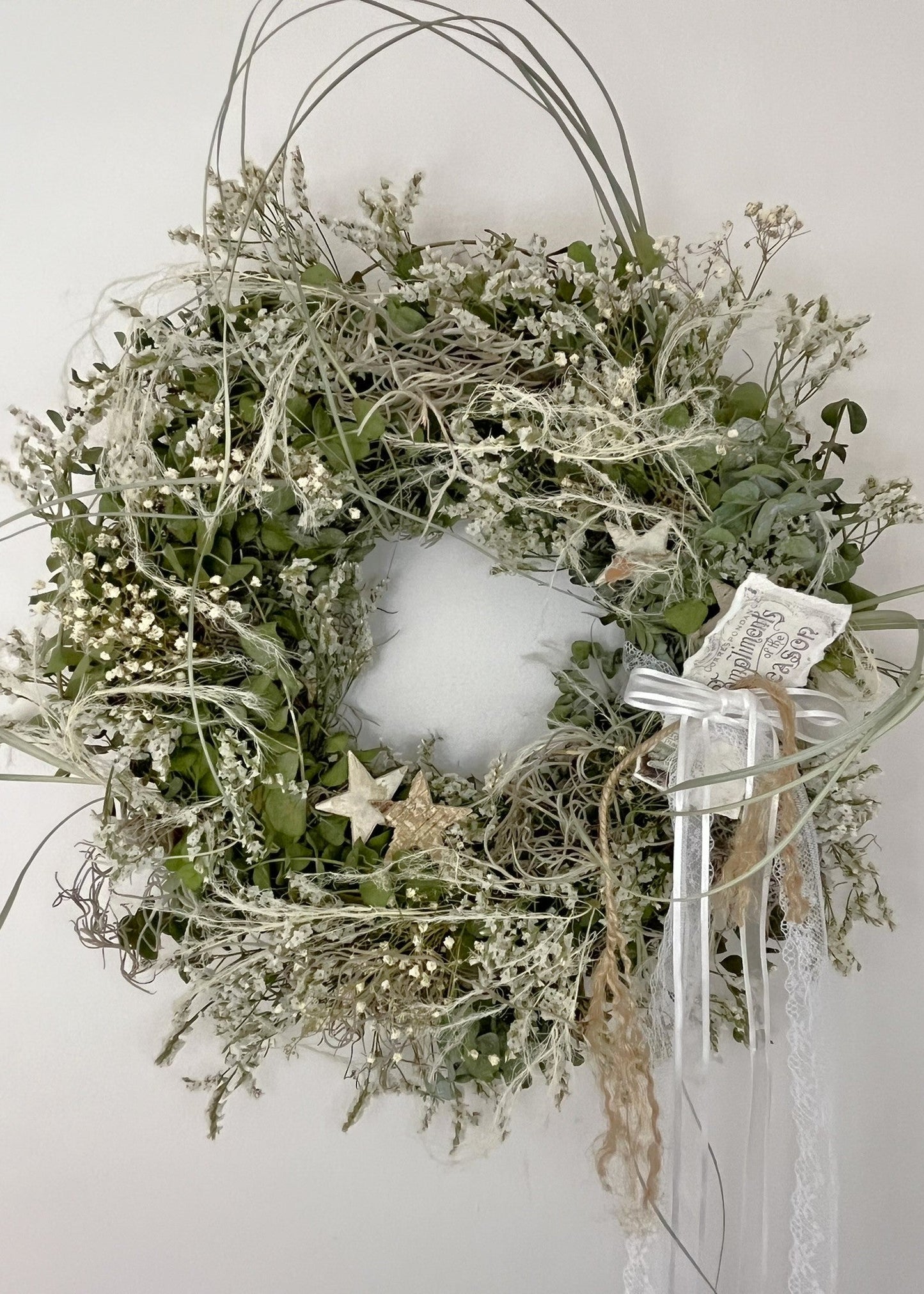 Decorative wreath with greenery, stars, and ribbons on a white background