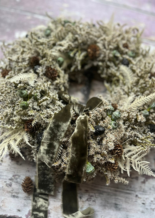 Wreath made of dried plants and moss on a wooden surface