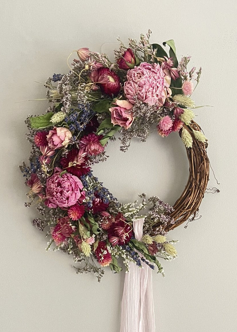 Floral wreath with pink and purple flowers on a plain wall
