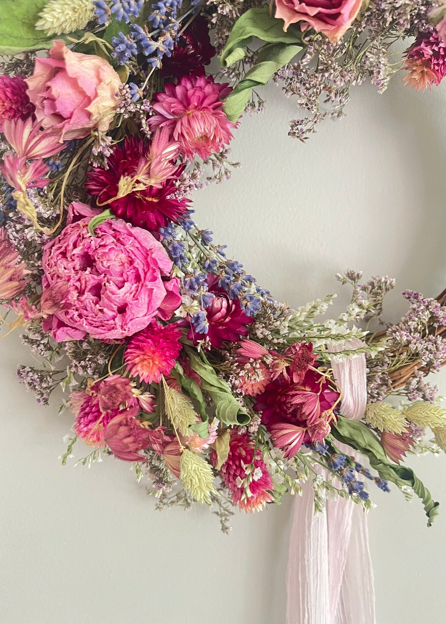 Floral wreath with pink and purple flowers on a white wall